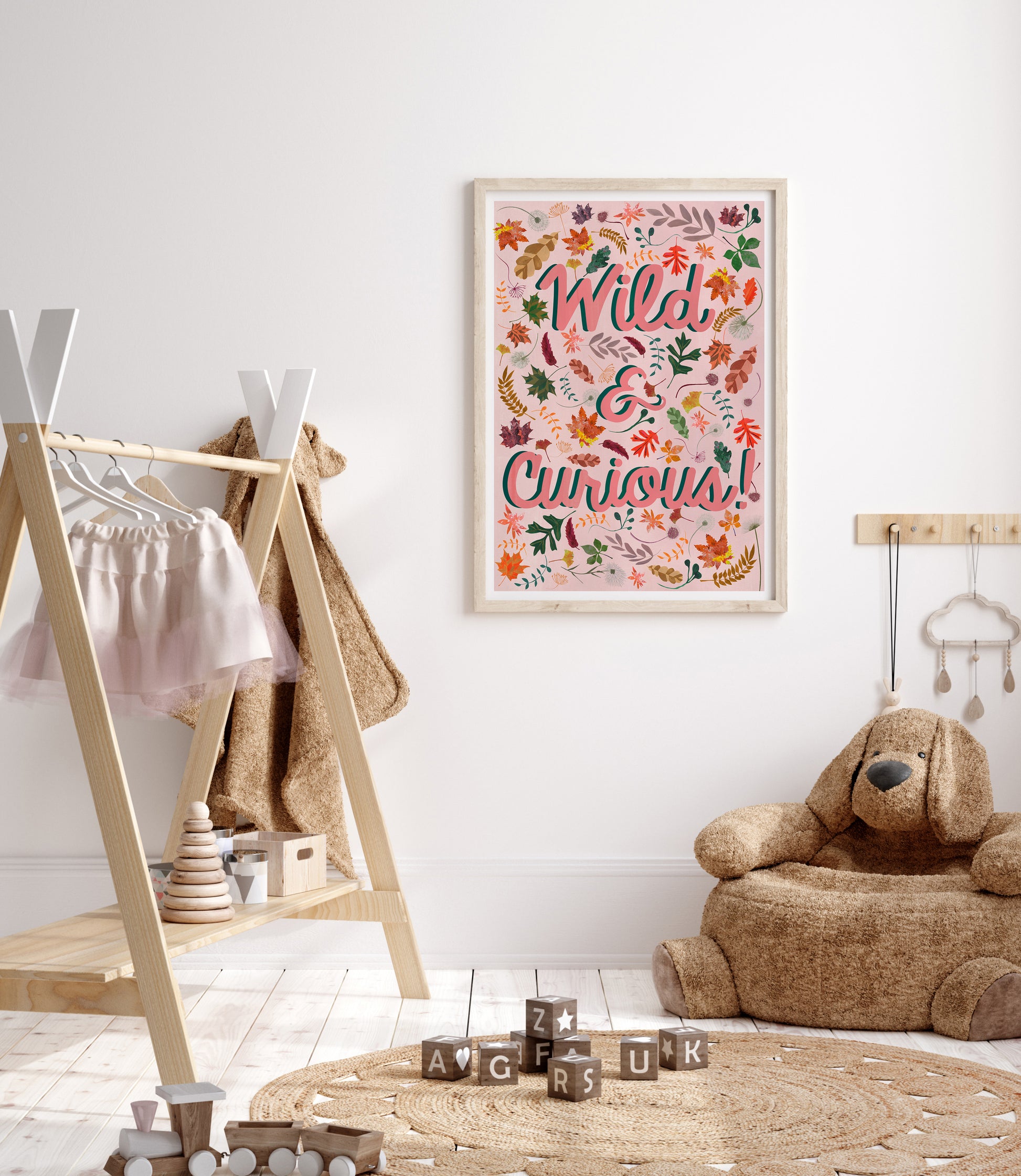 Children's room with a wooden teepee, teddy bear, and framed wild & curious woodland themed artwork on the wall.