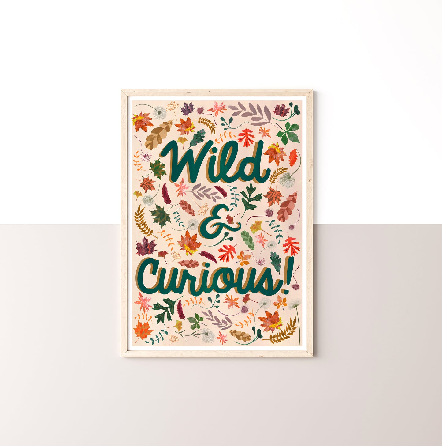 Framed artwork with 'Wild & Curious!' text and leaf designs on a neutralbackground