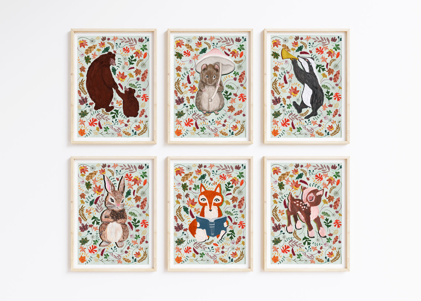 Six Hand Painted Woodland Animal prints surround by autumn leaes placed on a pale gren background colour, framed and place on a white wall.