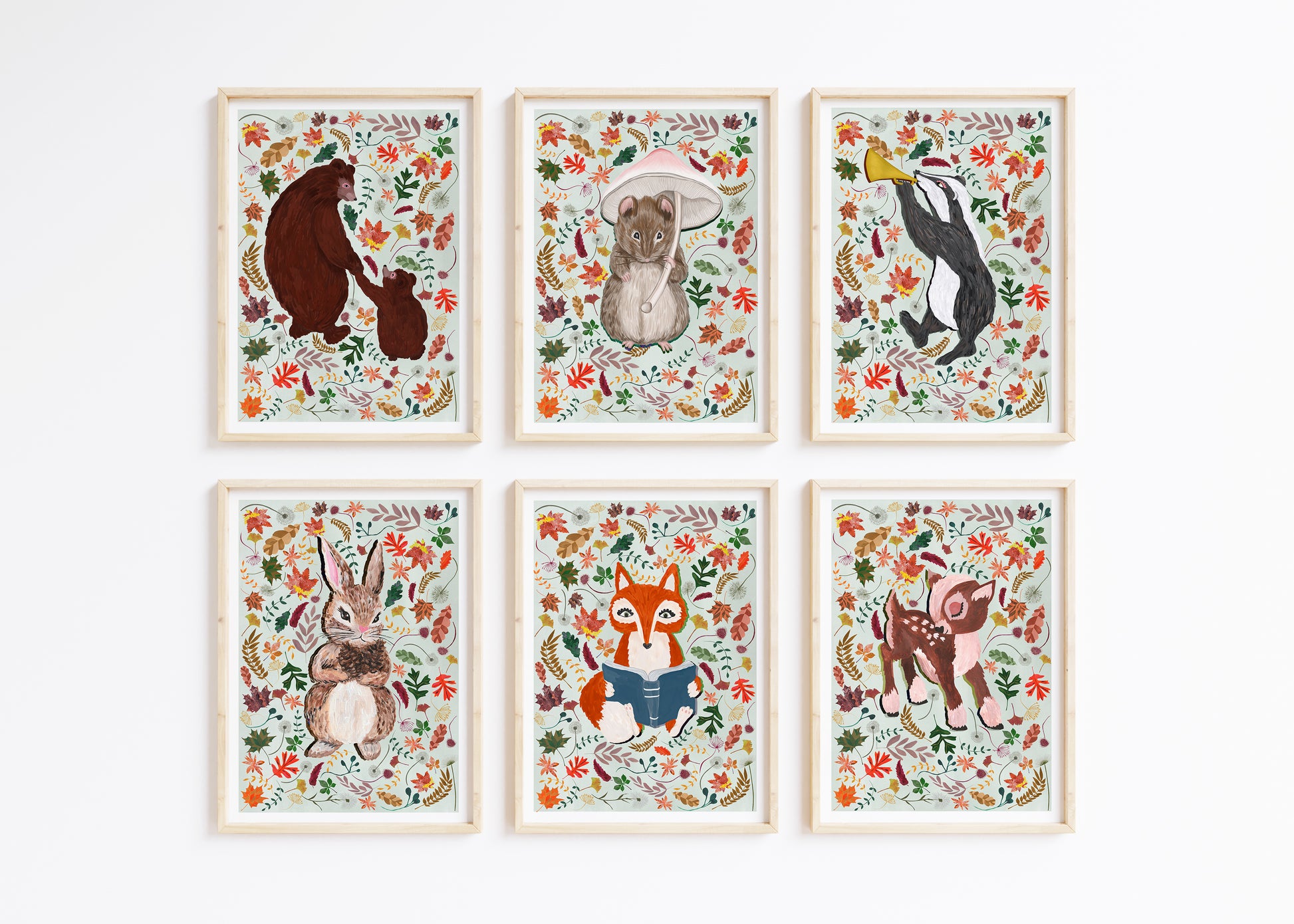 Six Hand Painted Woodland Animal prints surround by autumn leaes placed on a pale gren background colour, framed and place on a white wall.