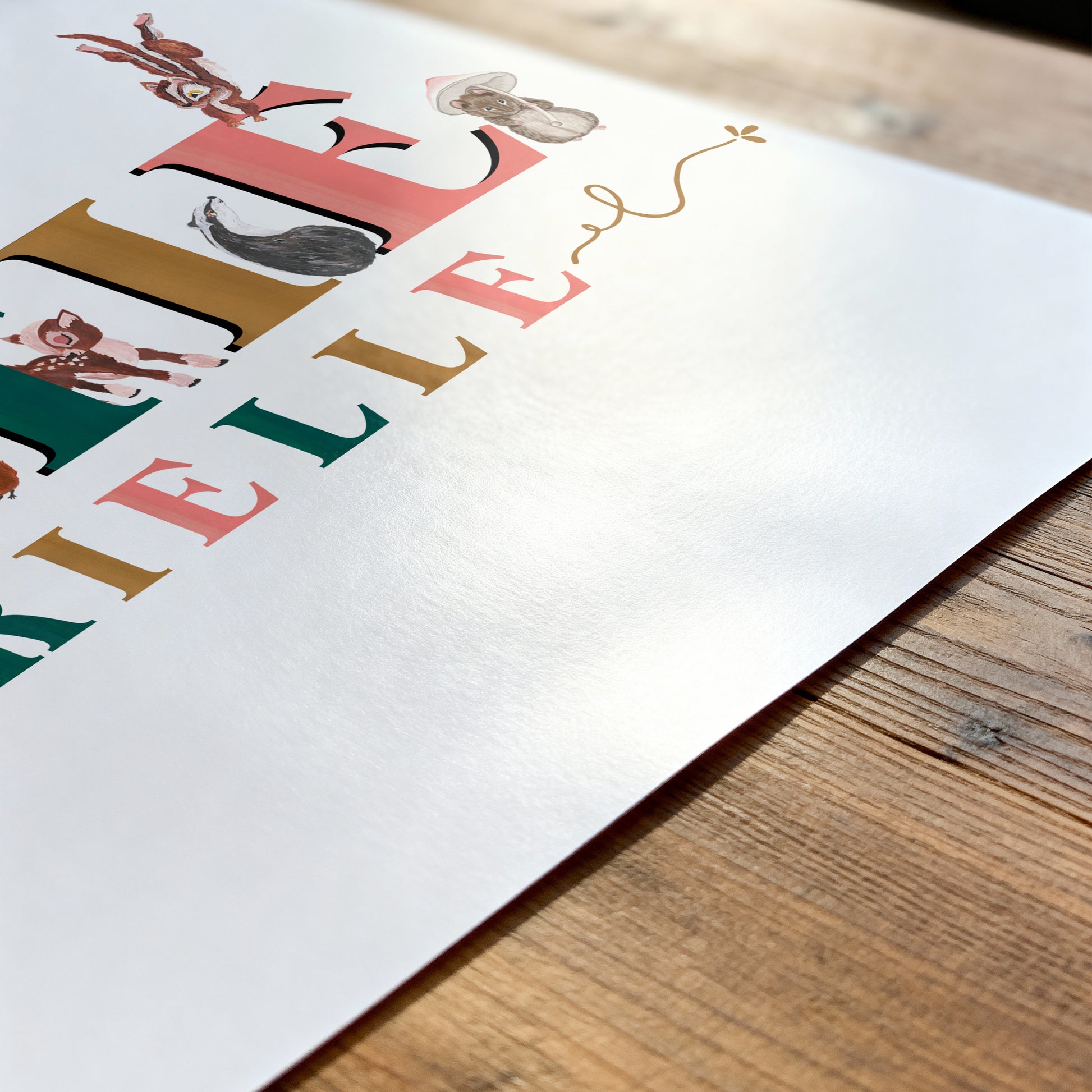 Colorful illustration of a childs name print on a white background with wooden surface below
