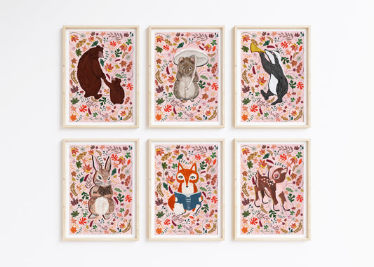A set of 6 woodland animal prints, of a bear, mouse, badger, rabbit, fox and deer suurounds by autumn leaves on a pale pink background, framed on a white wall