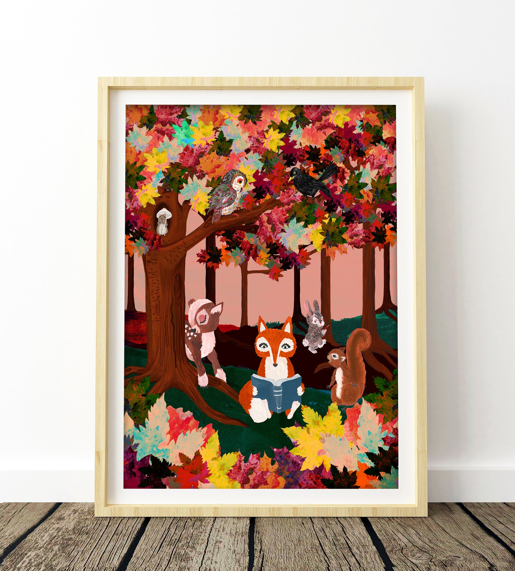 Framed artwork of animals in a forest with colorful leaves on a wooden floor.