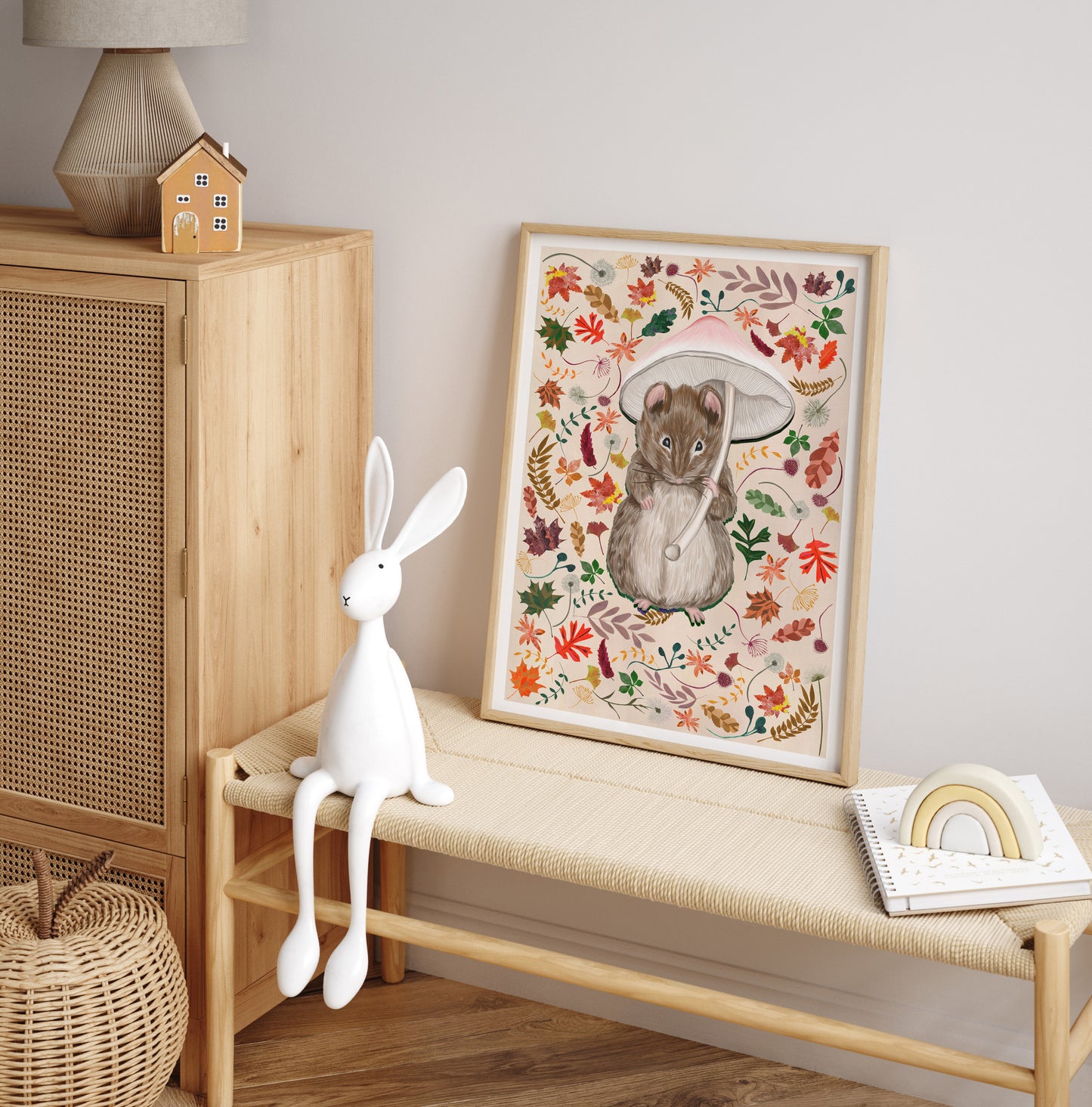 Decorative scene with a framed mouseprint, white rabbit figurine, and wooden cabinet.