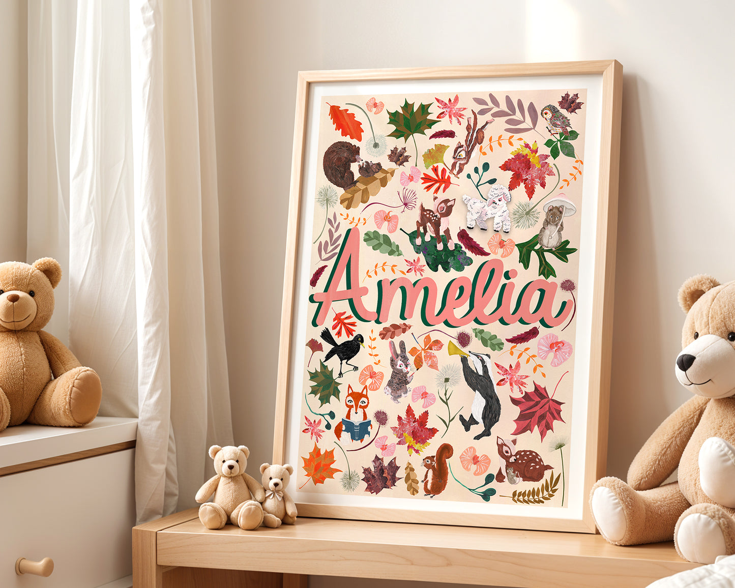 Framed artwork with 'Amelia' surrounded by colorful animals and flowers, placed on a wooden surface with teddy bears.