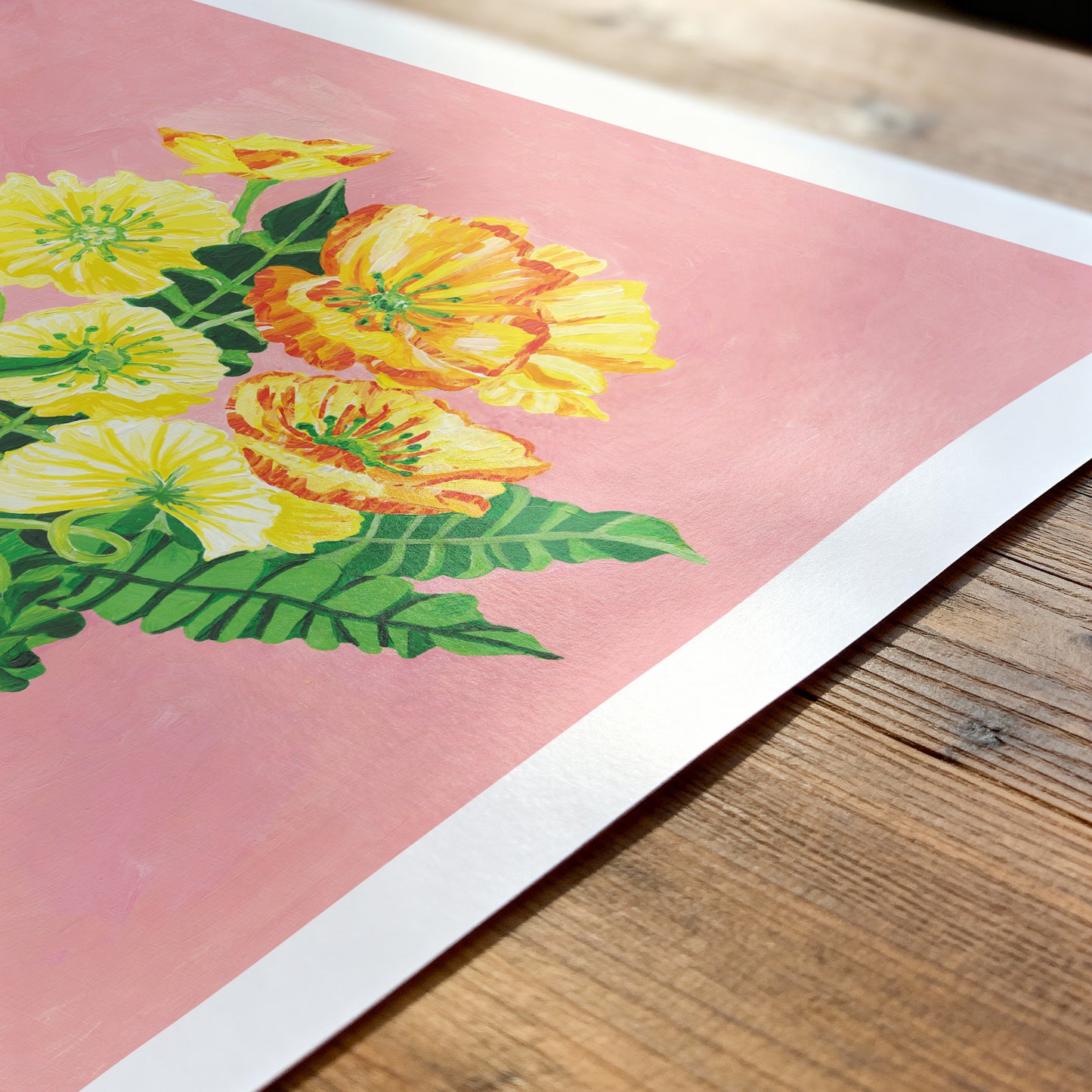 Floral illustration on pink paper with green leaves, placed on a wooden surface.