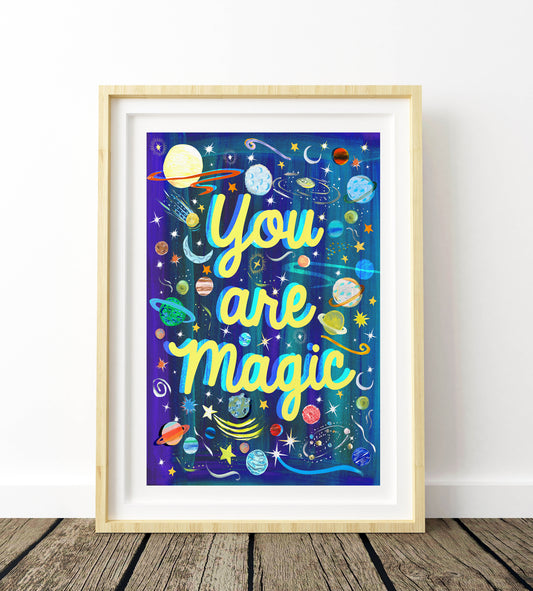 Framed artwork with 'You are Magic' text and space-themed design on a wooden floor.