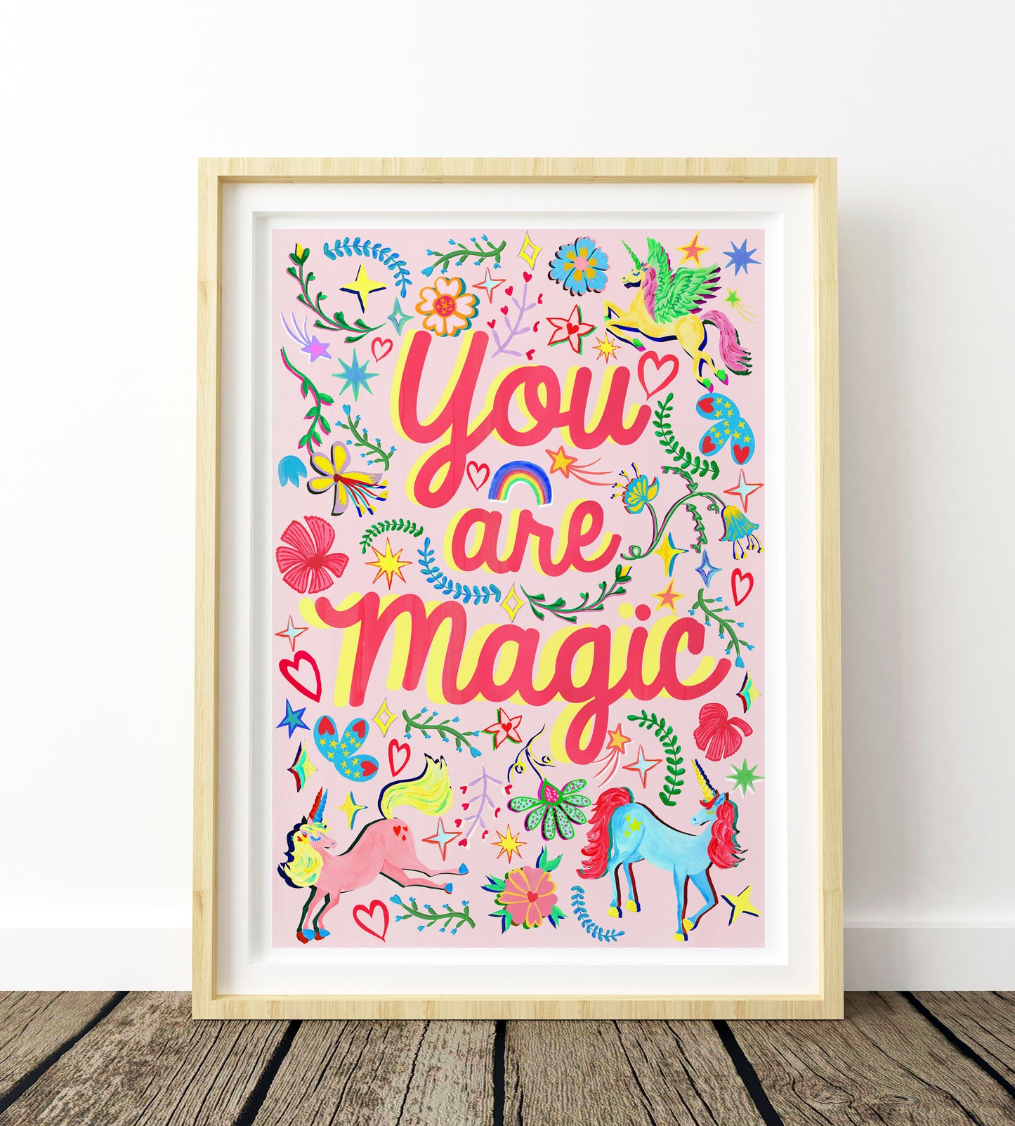 Framed colorful artwork with 'You are magic' text on a wooden floor.