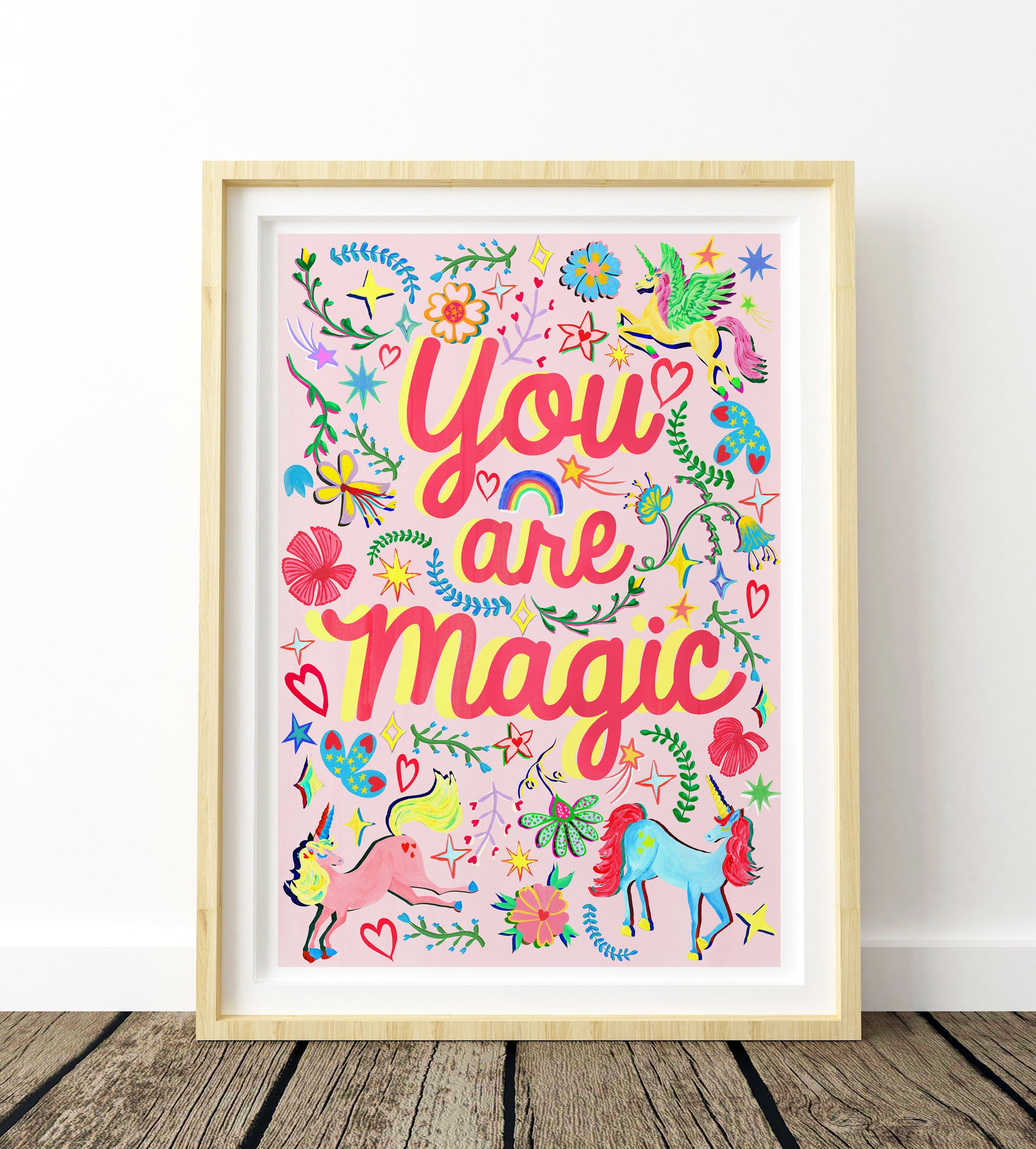Framed colorful artwork with 'You are magic' text on a wooden floor.