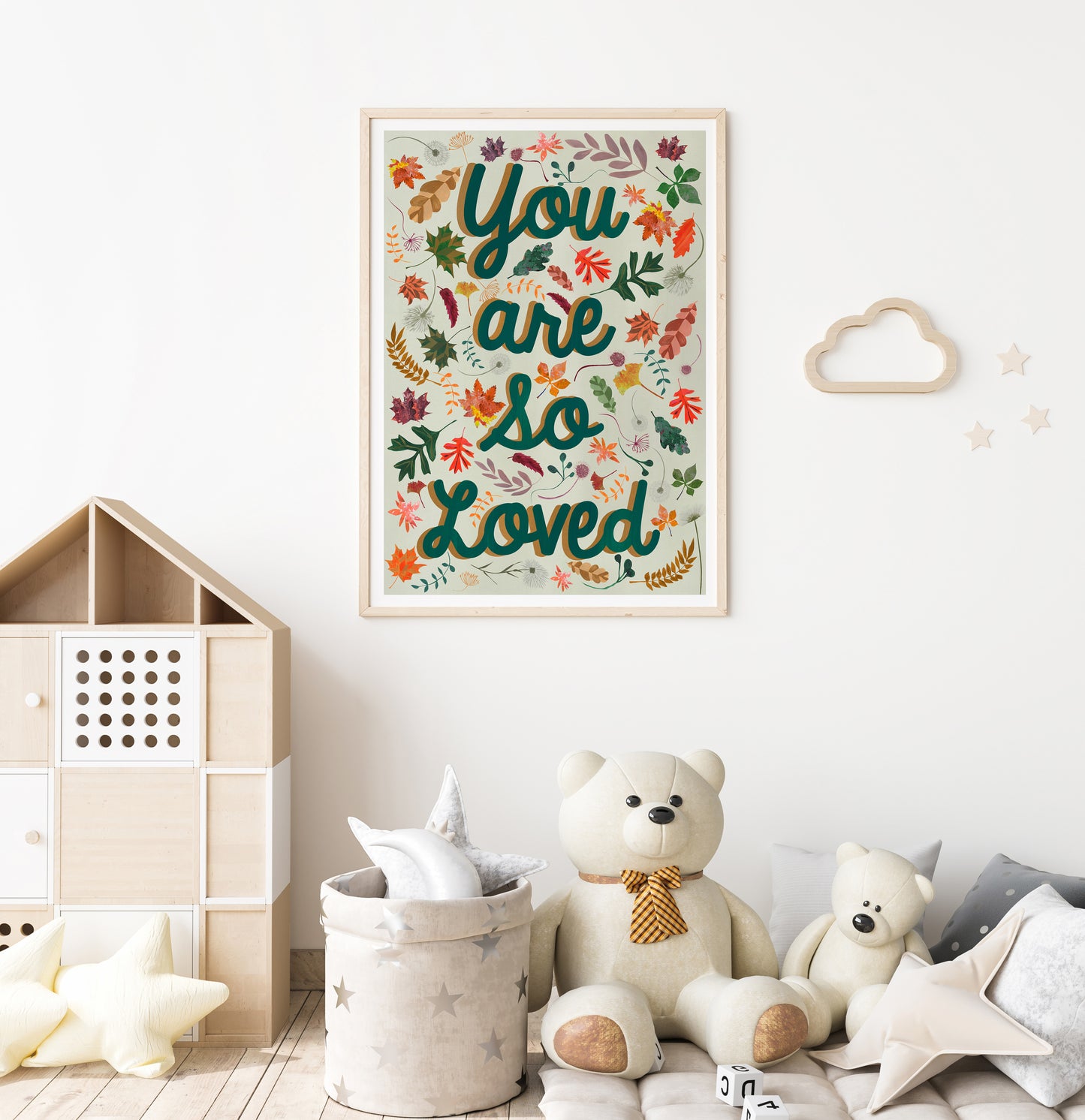 Framed artwork with 'You are so loved' text in a child's room with toys and decor.