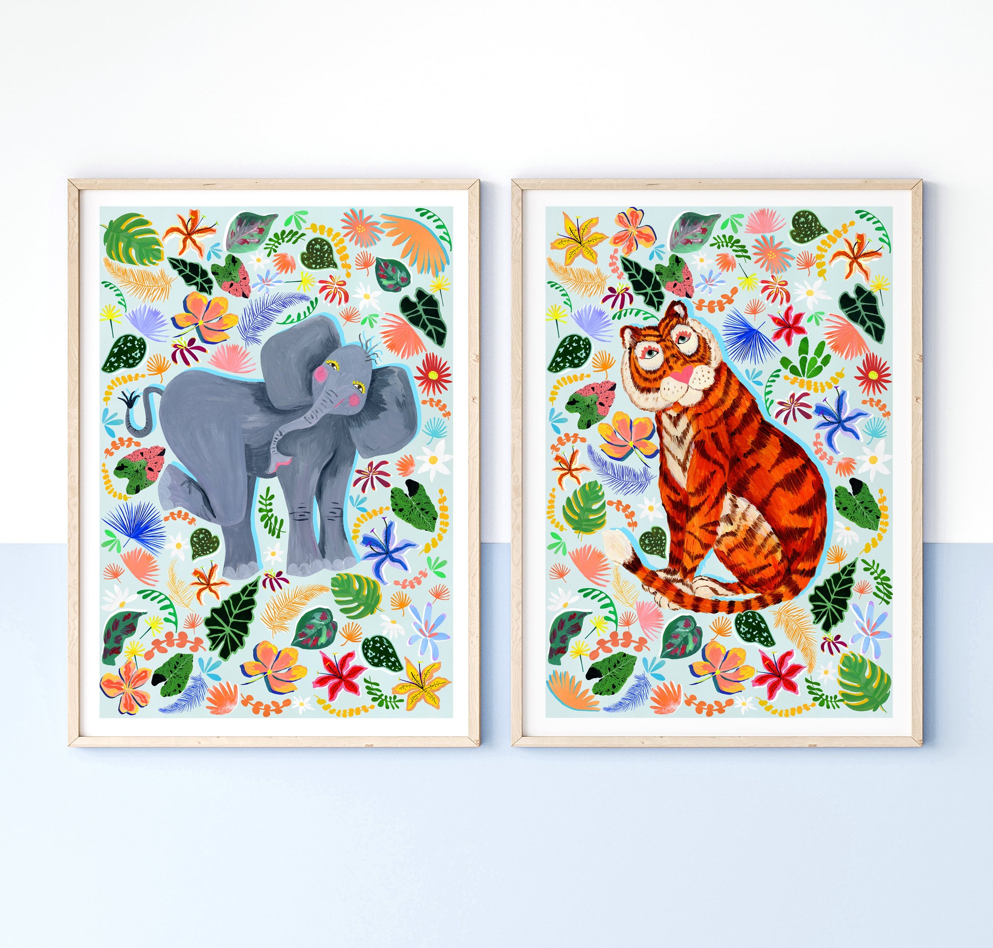 Two framed illustrations of an elephant and a tiger surrounded by colorful floral and leaf patterns on a white background.