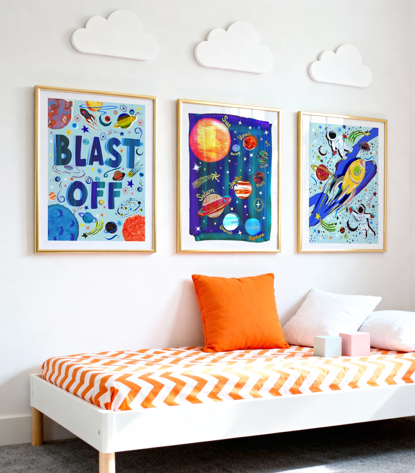 Children's room with space-themed wall art and a bed with orange and white bedding.
