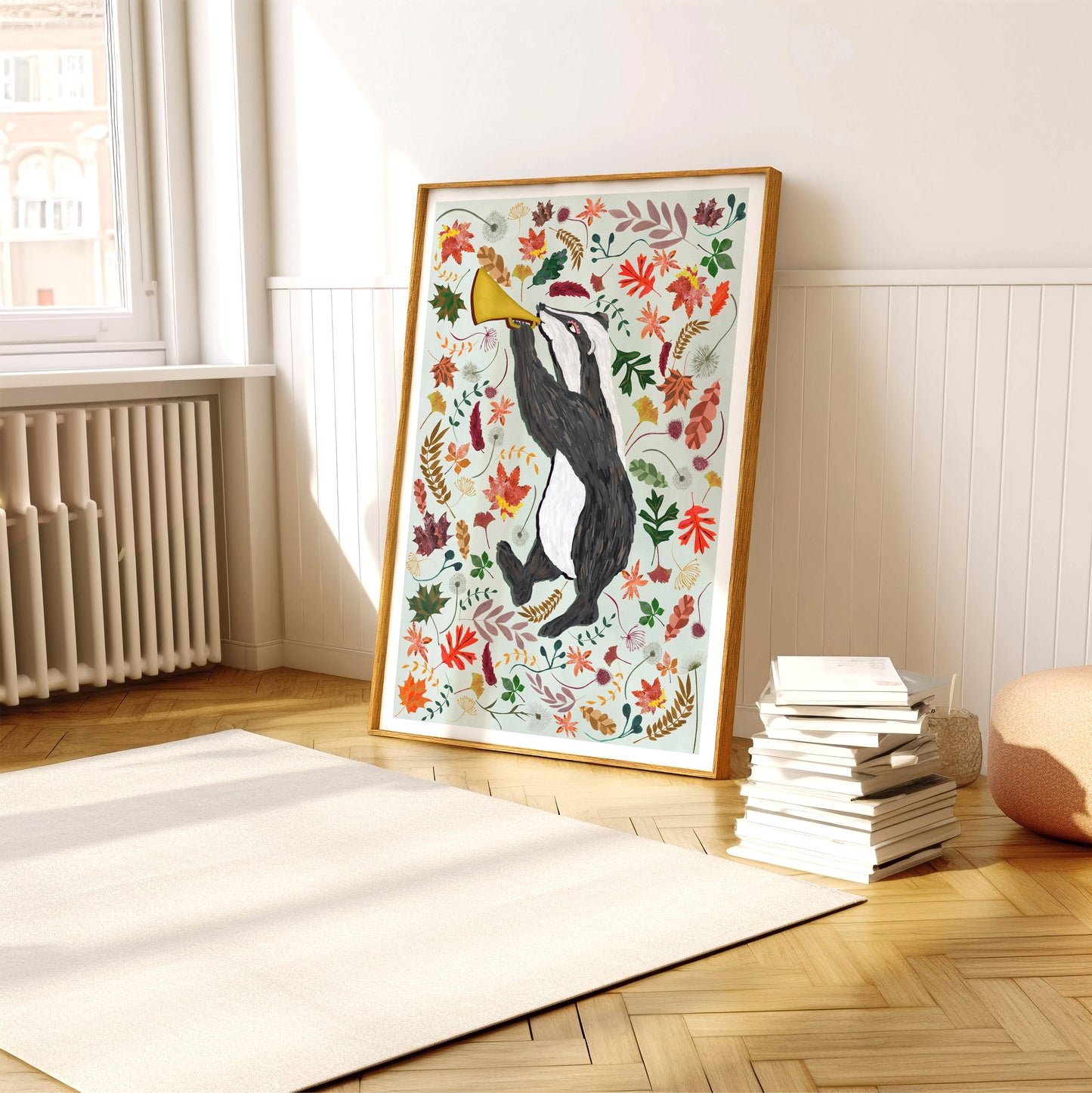 Framed artwork of a penguin with autumn leaves in a room with a window and books.