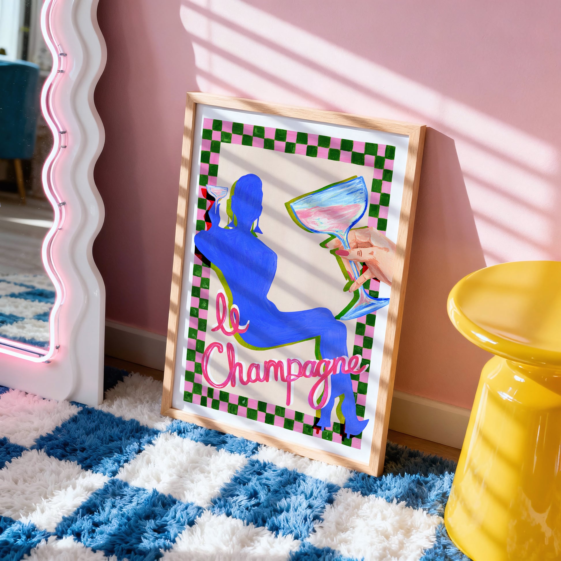 Framed artwork with a blue silhouette and 'le Champagne' text on a checkered background, placed on a blue and white checkered rug.