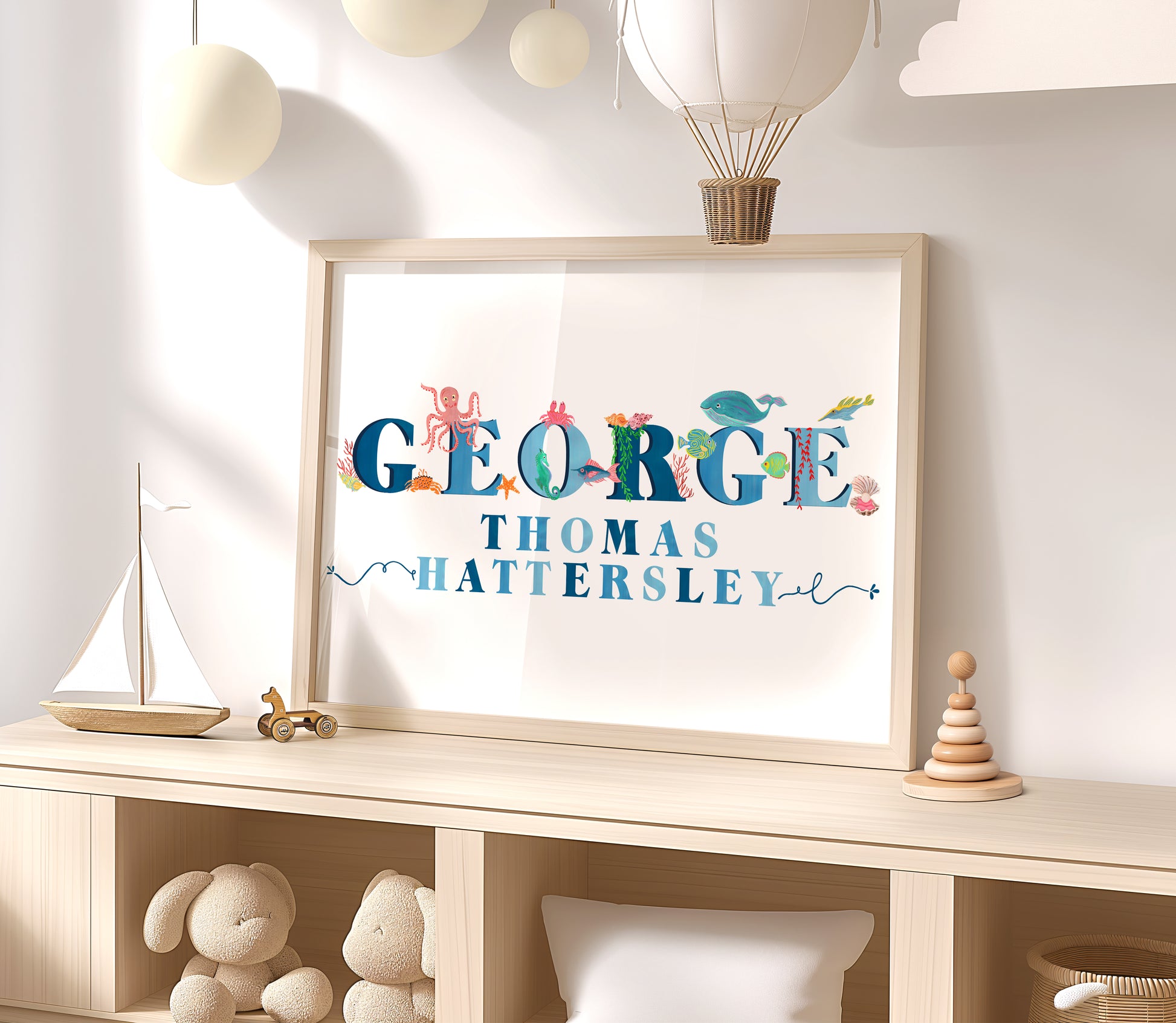 Framed name print with  sea animal illustrations with decorative elements on a shelf in a child's room