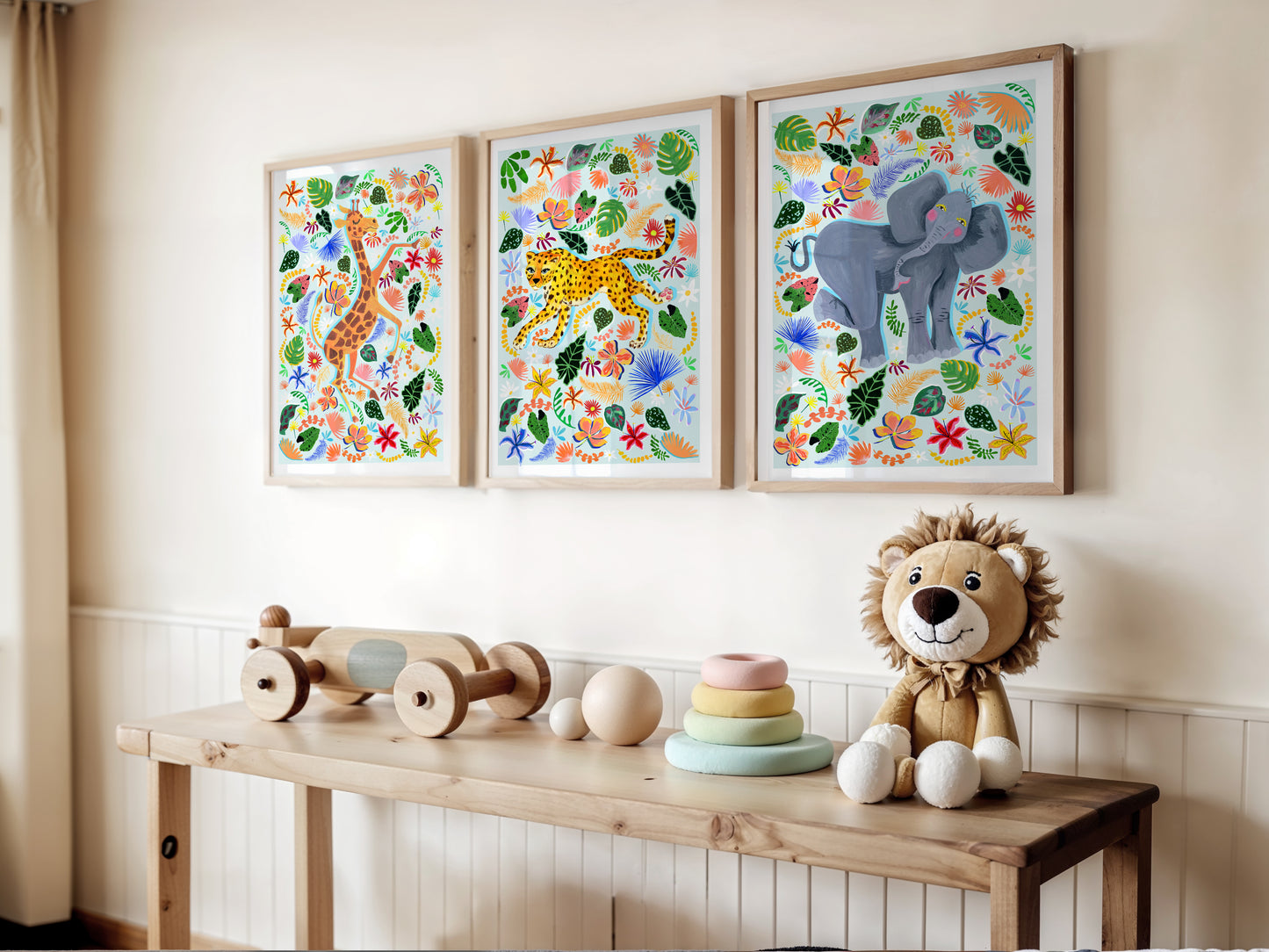Three colorful animal prints on a wall above a wooden bench with toys.