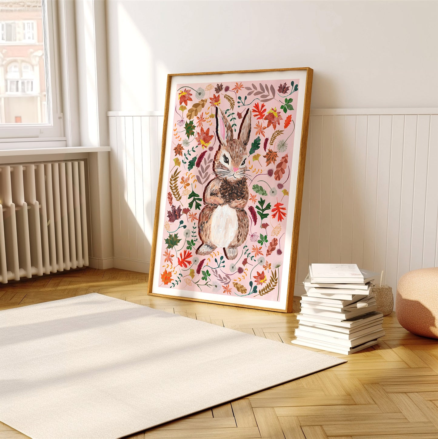 Framed artwork of a rabbit surrounded by flowers on a wall in a room with books and a radiator.
