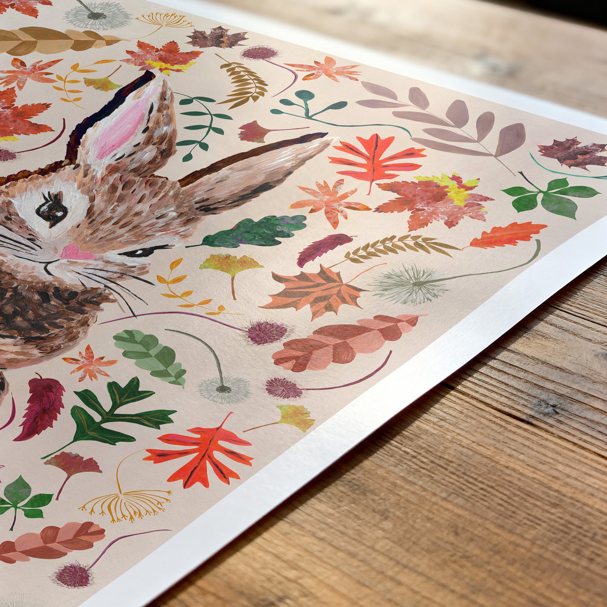 Decorative paper with rabbit illustration and autumn leaves on a wooden surface