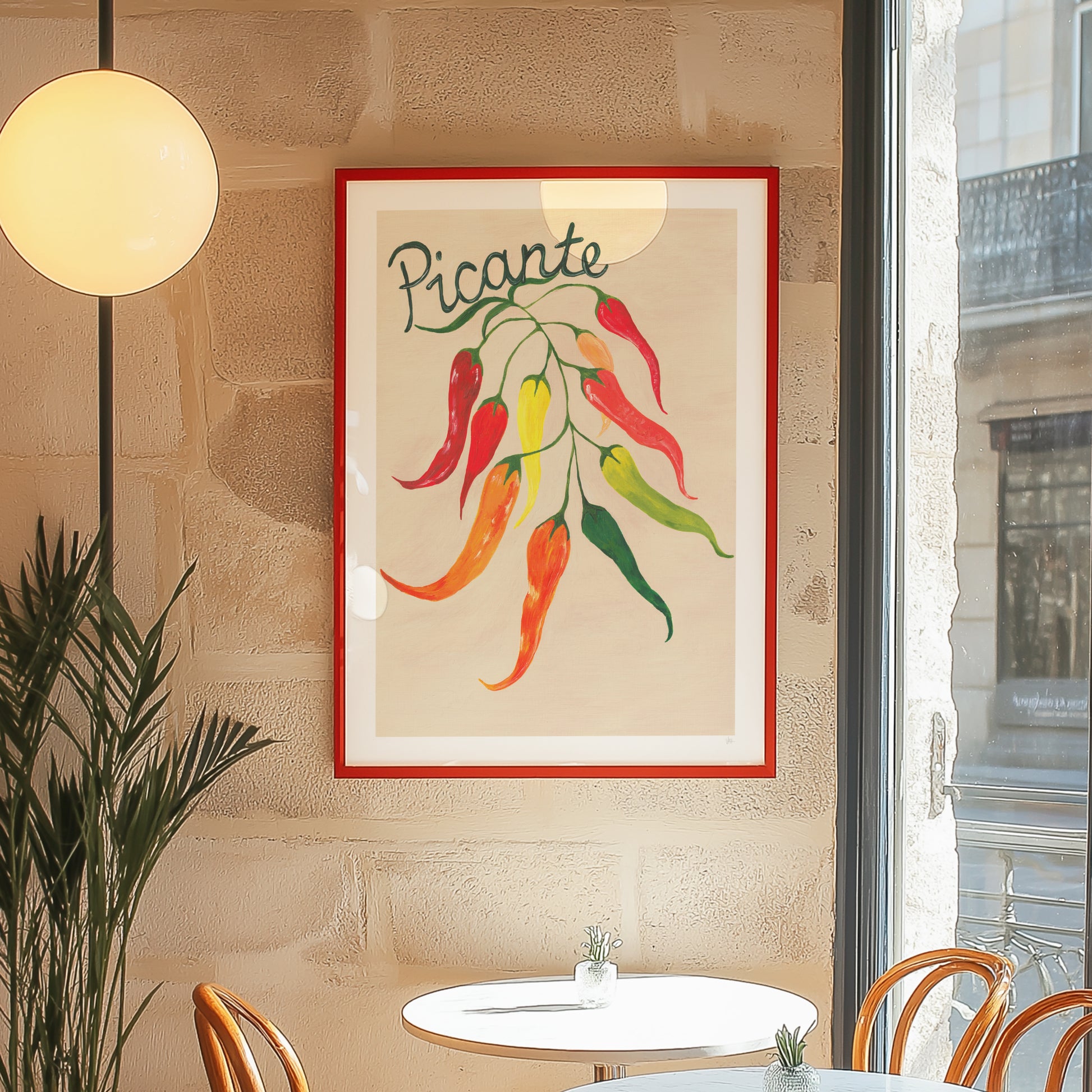 Framed artwork of peppers with 'Picante' text on a wall in a restaurant setting.