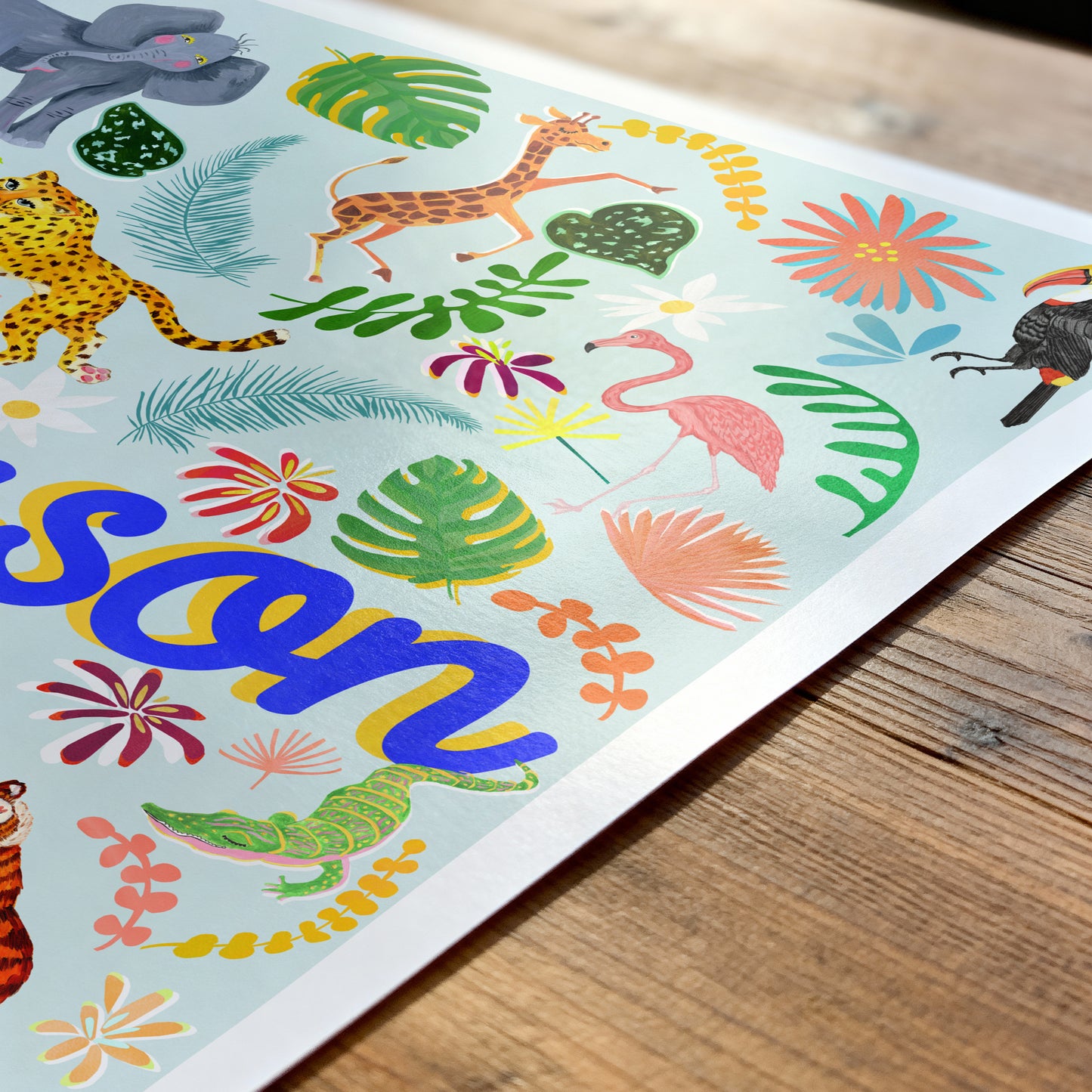 Colorful children's name placemat with animals and plants on a wooden surface