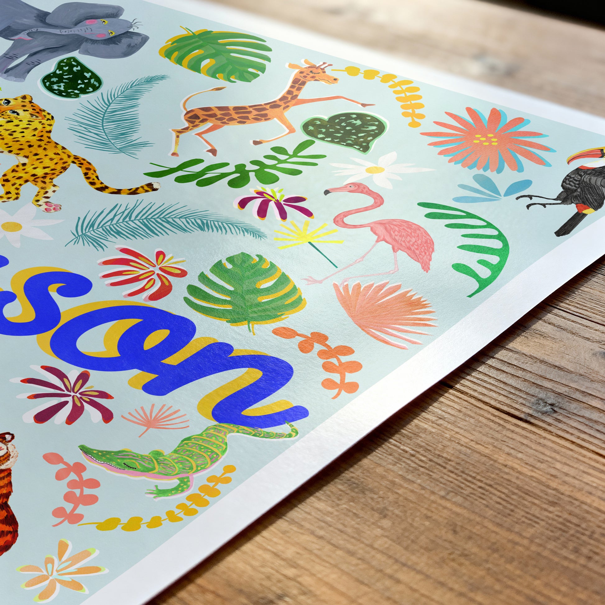 Colorful children's name placemat with animals and plants on a wooden surface