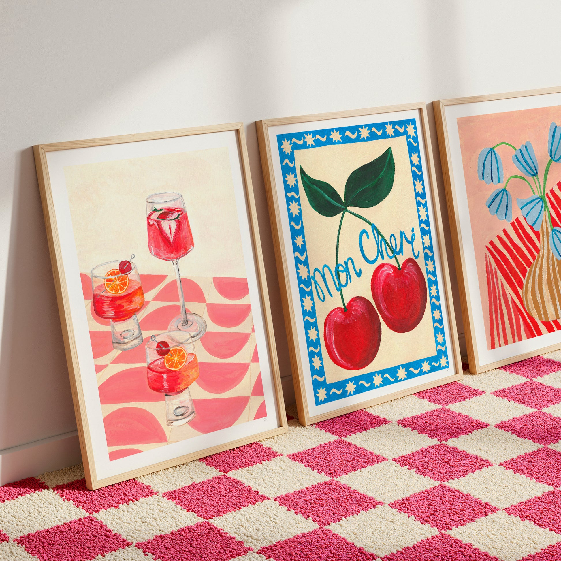 Three framed artworks on a pink and white checkered floor.