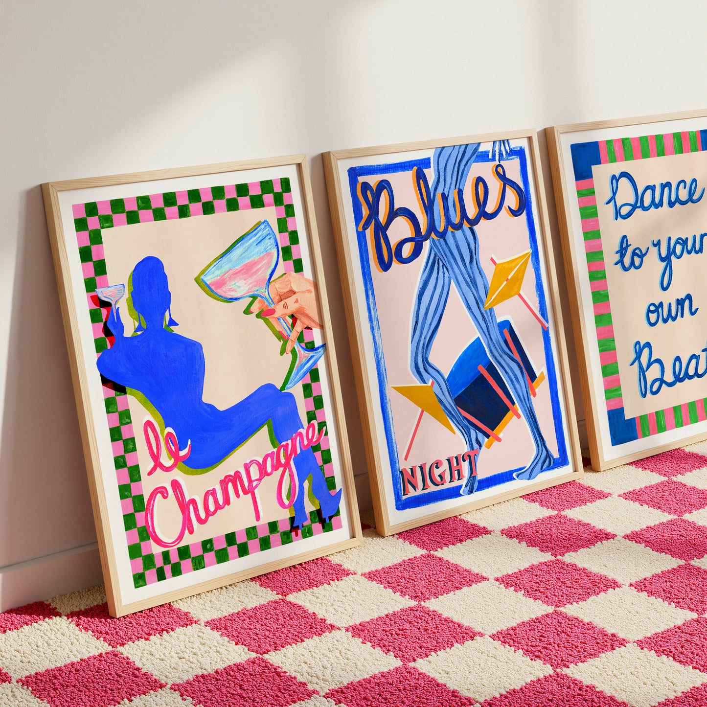 Three colorful framed artworks on a pink and white checkered floor.