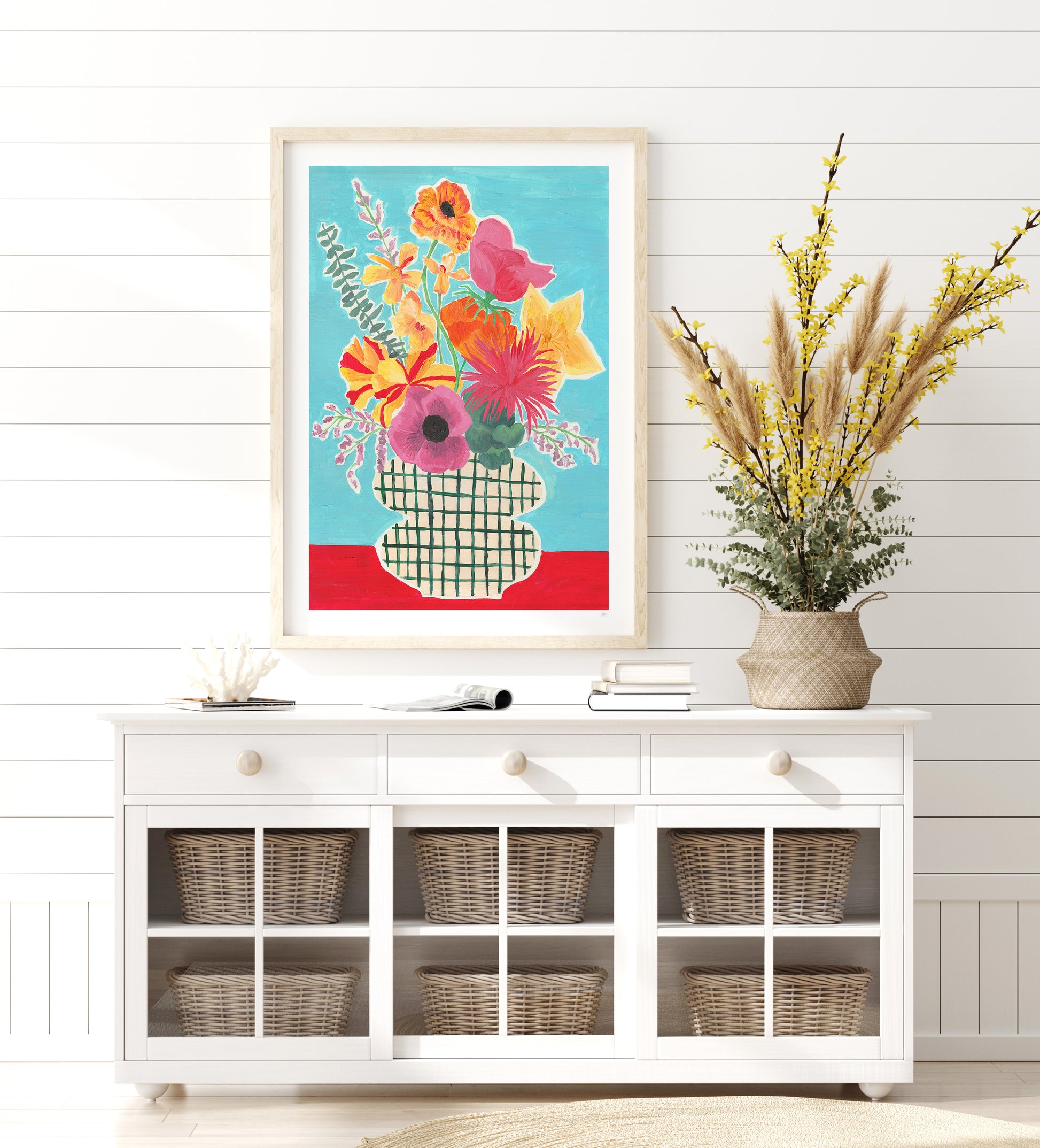 Colorful floral artwork on a white wall above a white cabinet with wicker baskets.