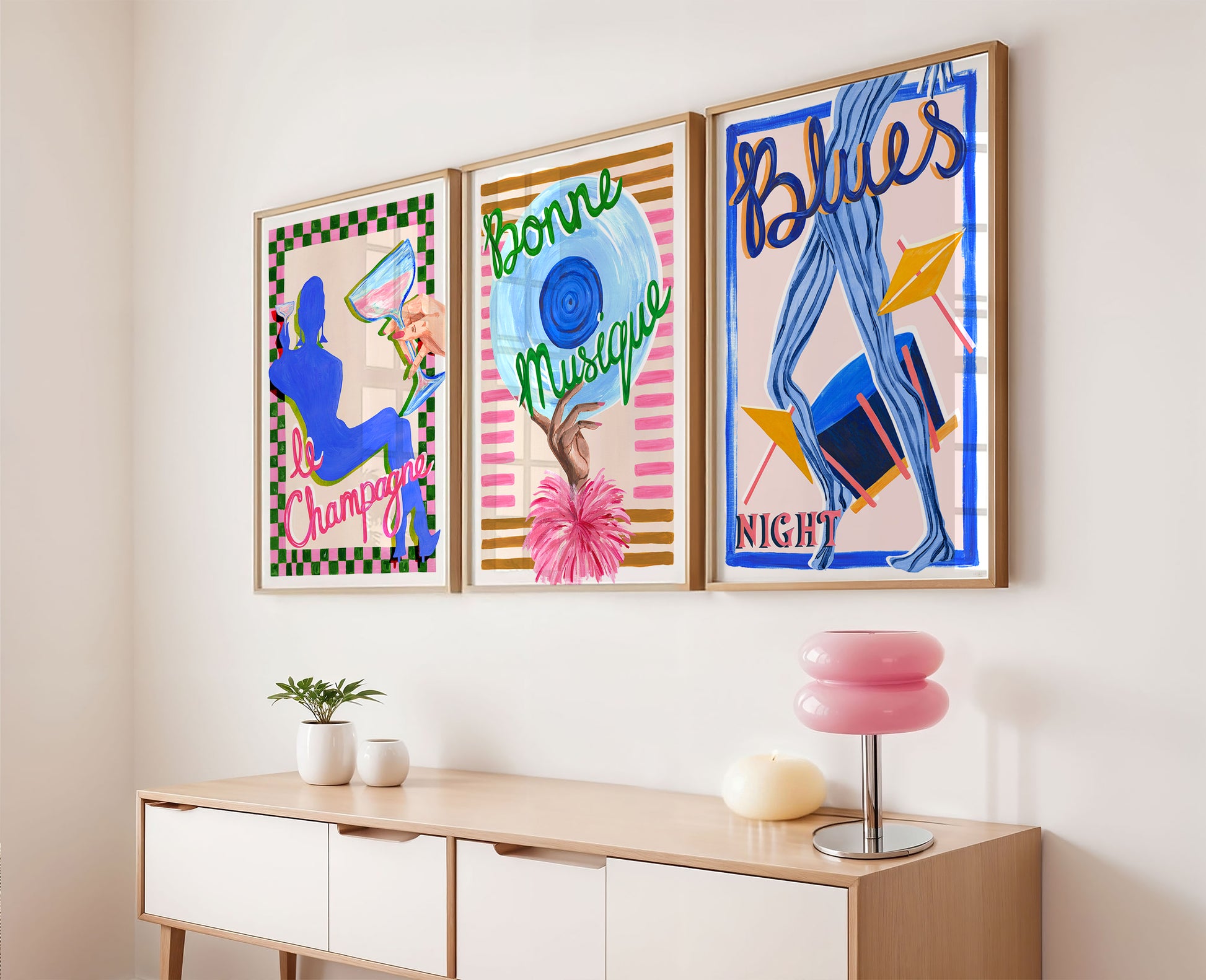 Three colorful framed artworks on a wall above a wooden console table.