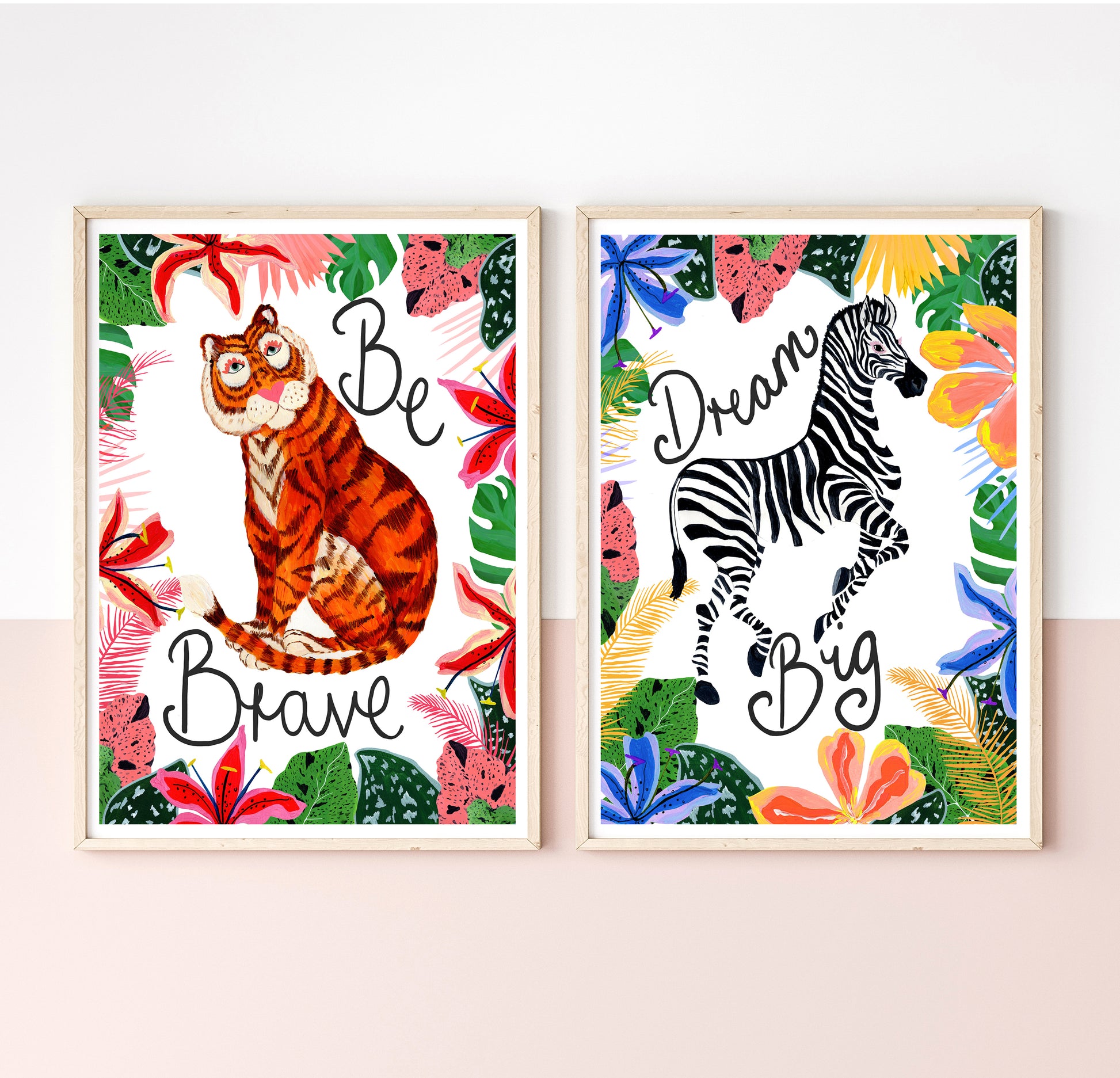 Two framed animal-themed prints with motivational phrases on a white wall.