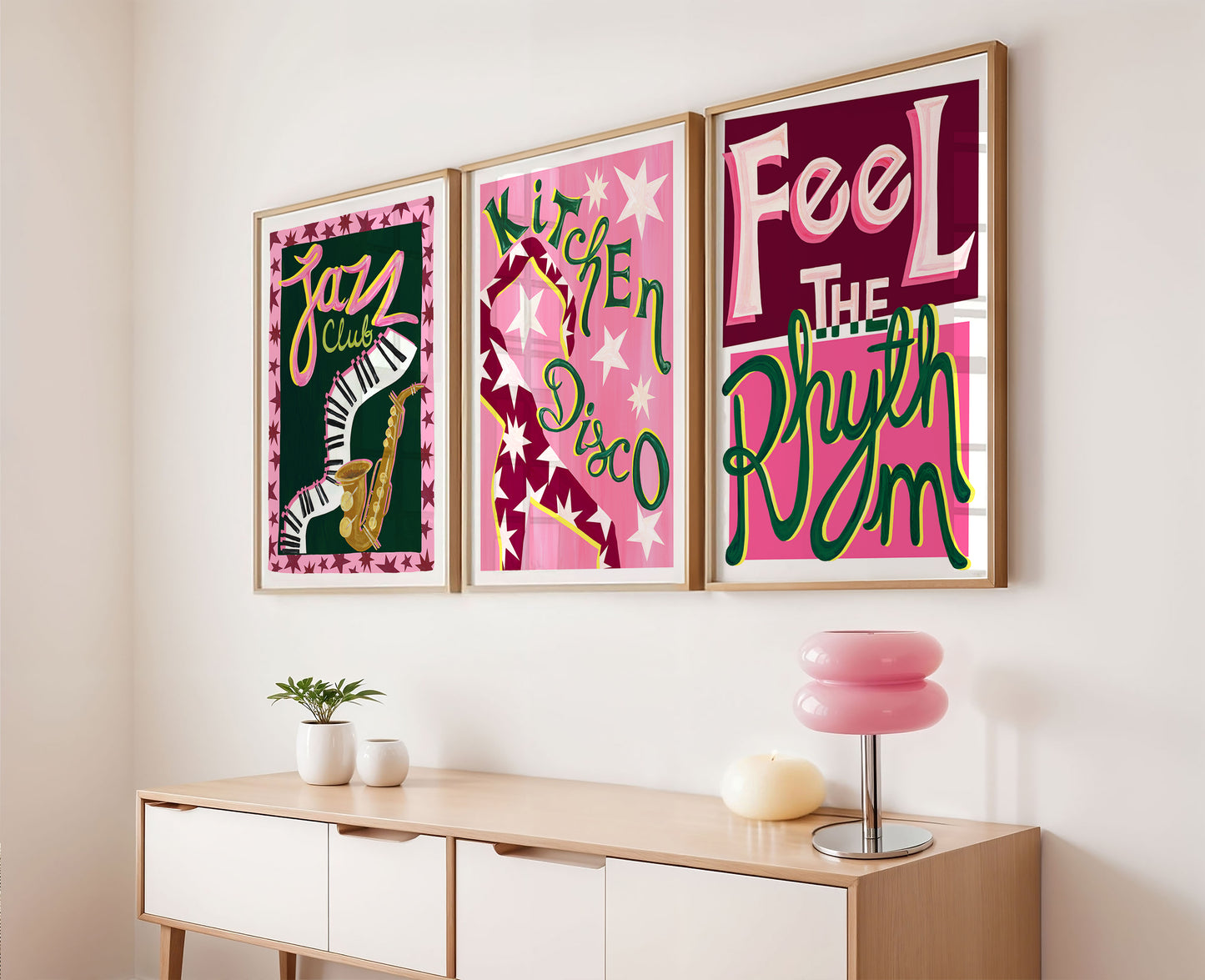 Three framed posters with colorful text and graphics on a wall above a wooden console table.