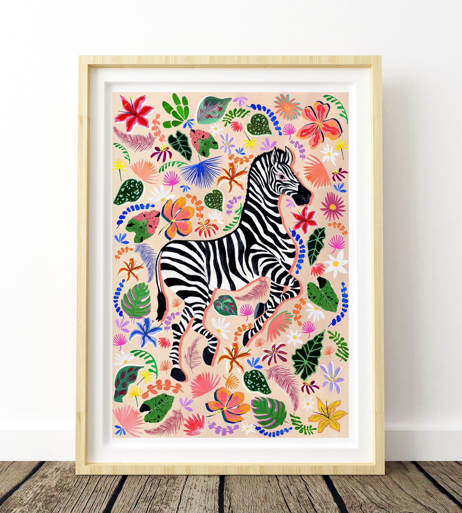 Framed artwork of a zebra surrounded by colorful flowers and leaves on a white wall.