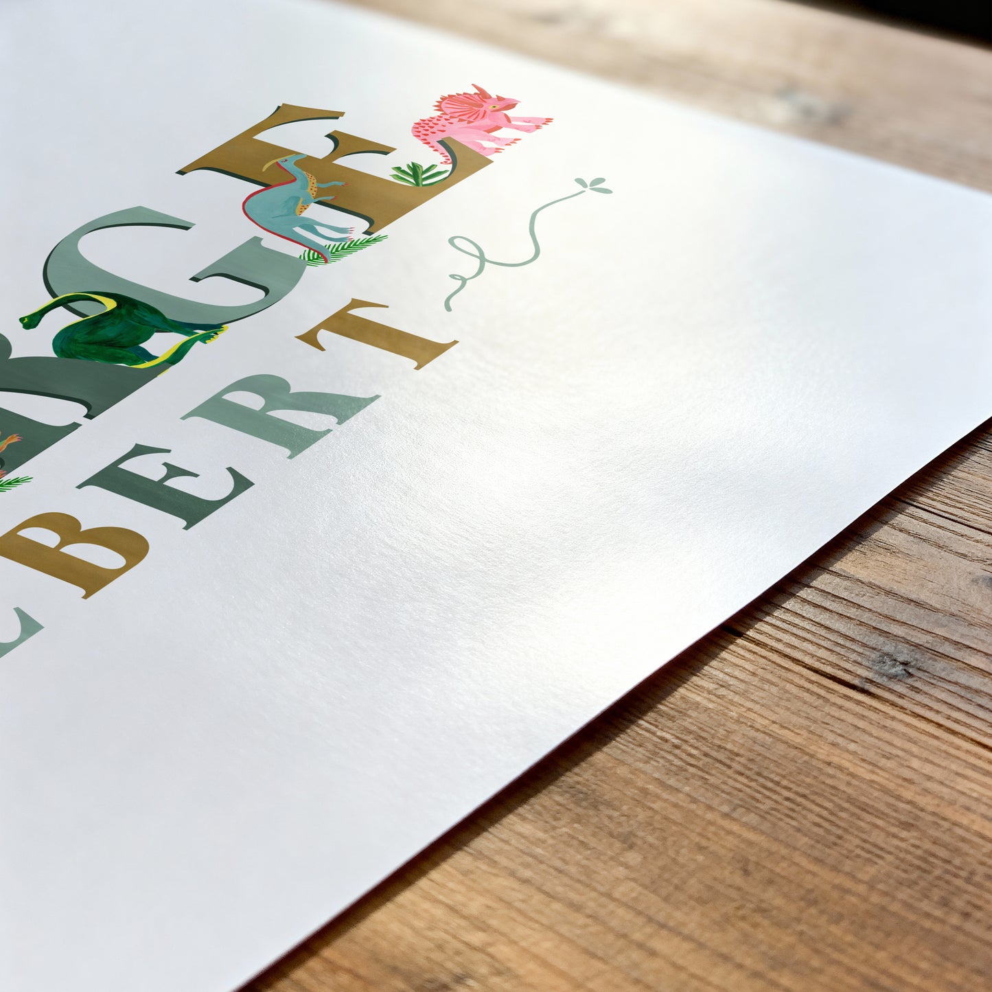 Colorful dinosaur name with dinosaur illustrations on a white paper with a wooden surface underneath