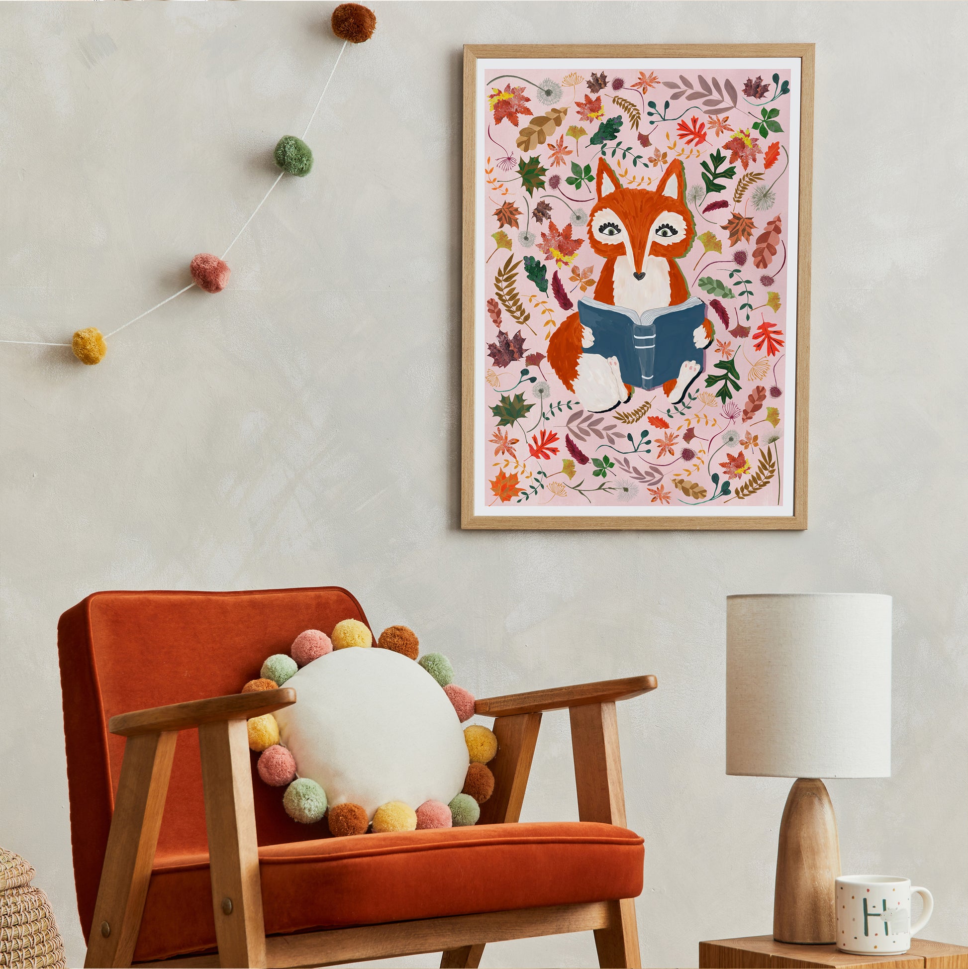 Framed artwork of a fox surrounded by autumn leave above an orange armchair with decorative elements.