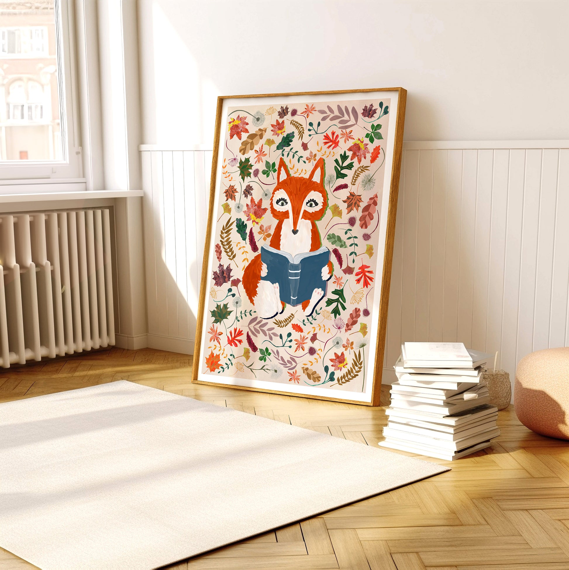 Framed artwork of a fox reading a book with autumn leaf patterns on a wall in a room.