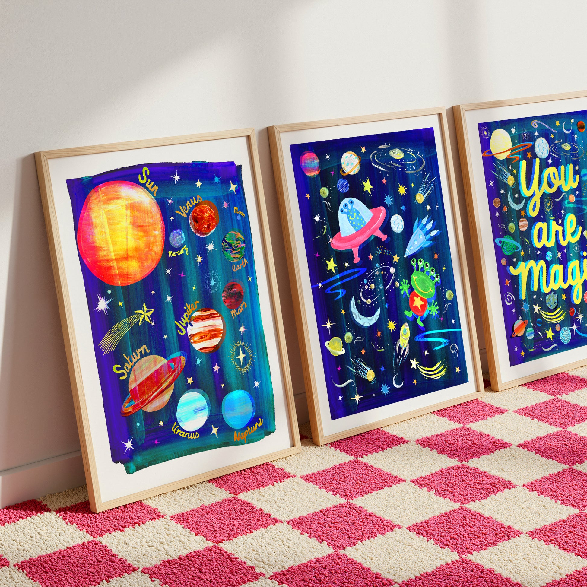 Three framed space-themed artworks on a checkered floor.
