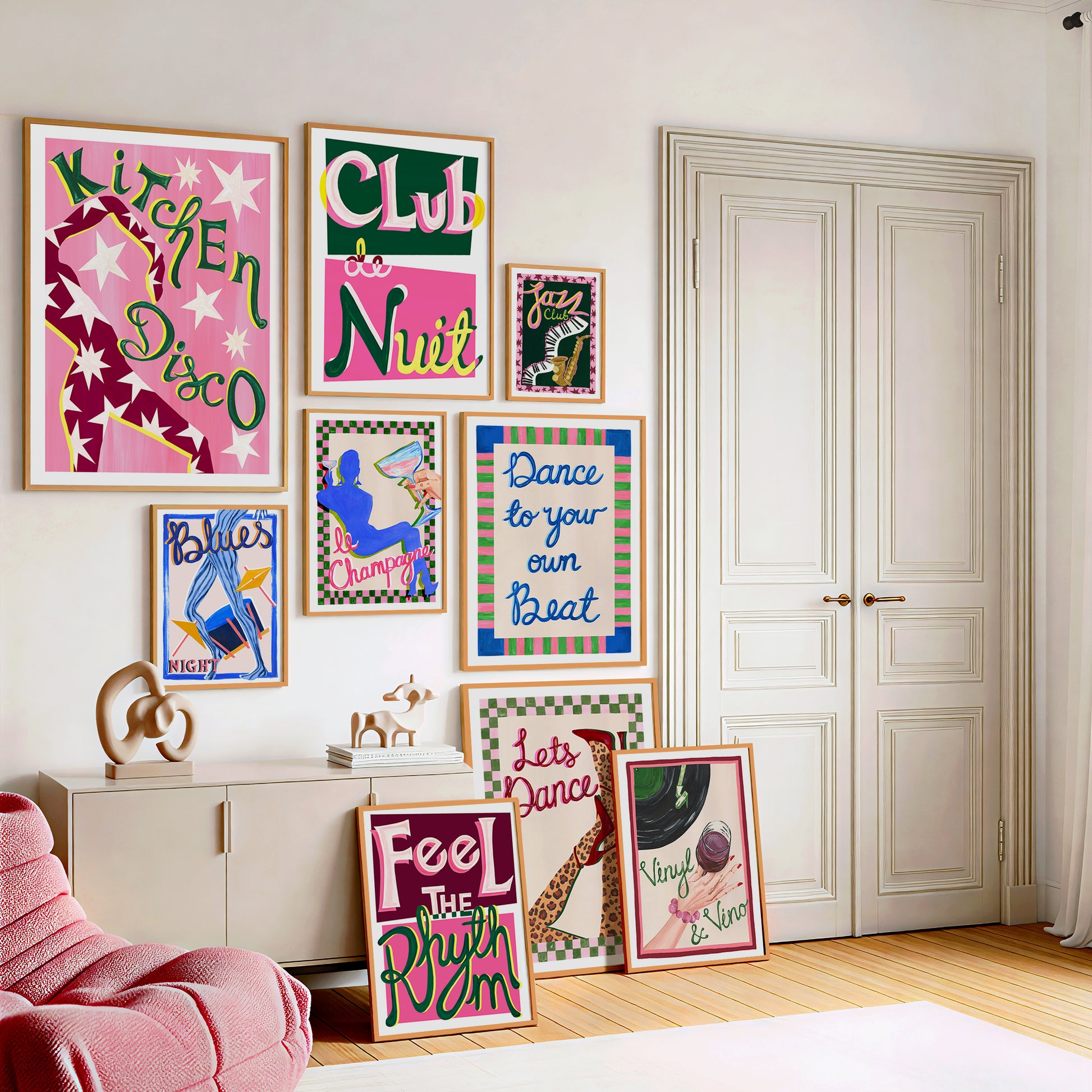 Colorful wall art prints in a room with a pink chair and white wardrobe.