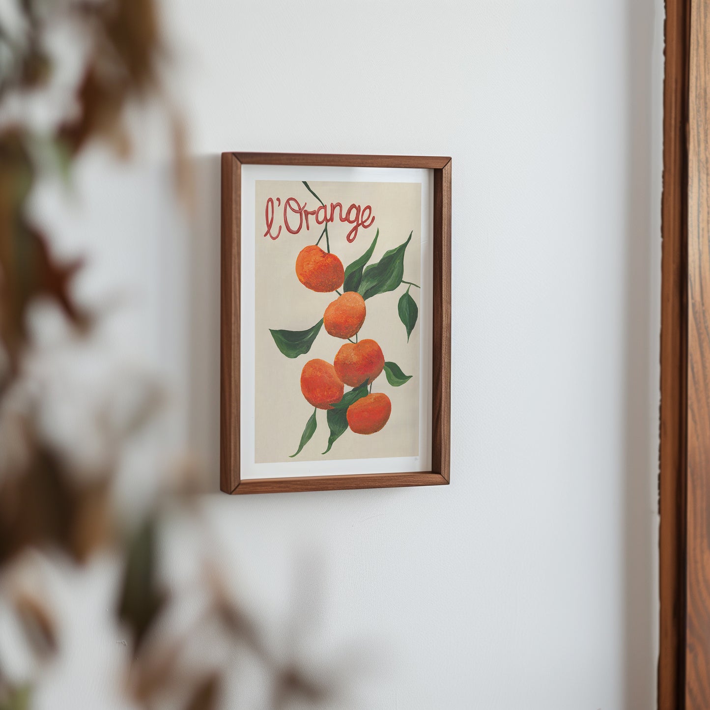 Framed artwork of oranges with 'L'Orange' text on a white wall.