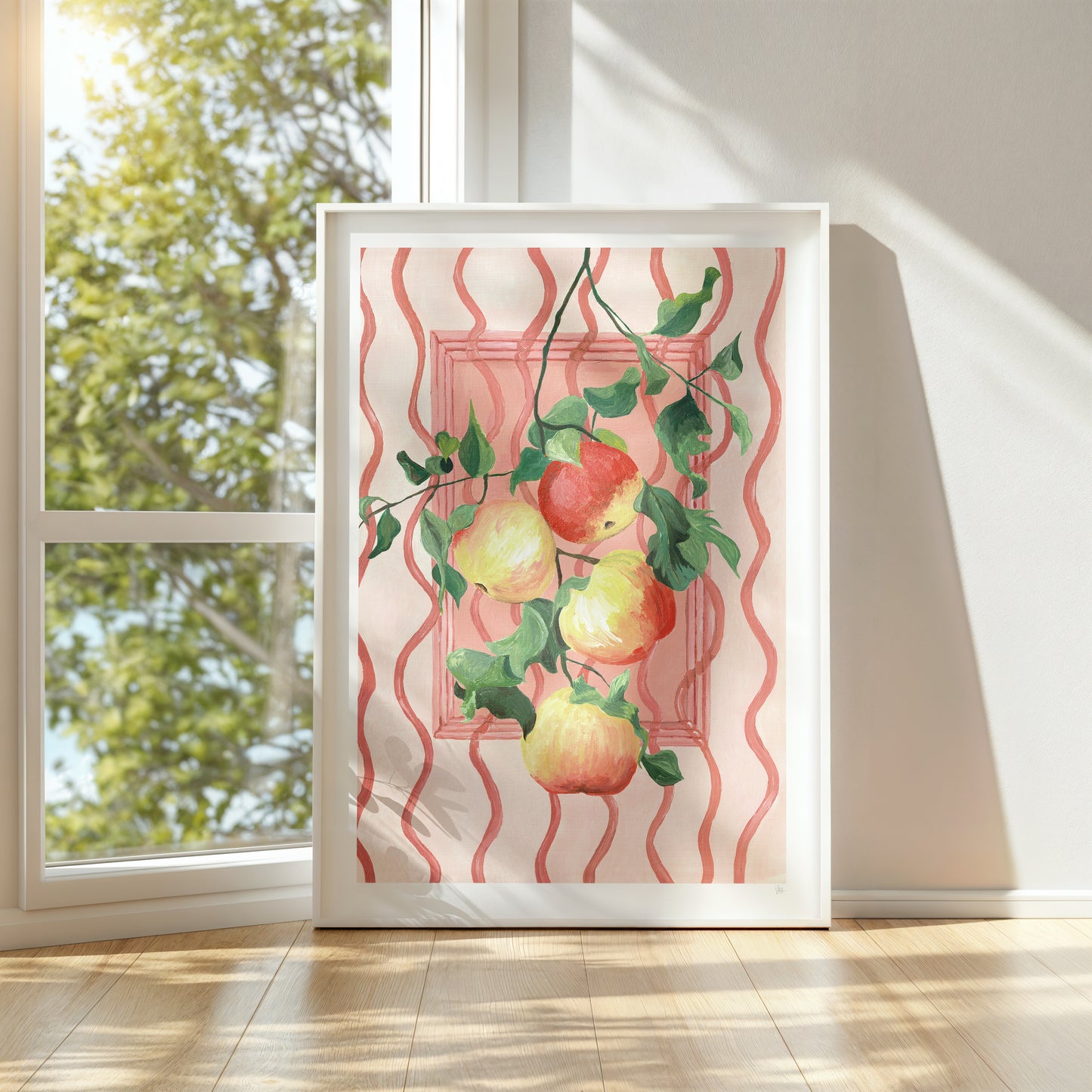 Framed artwork with apples on a decorative background in a bright room with a window.