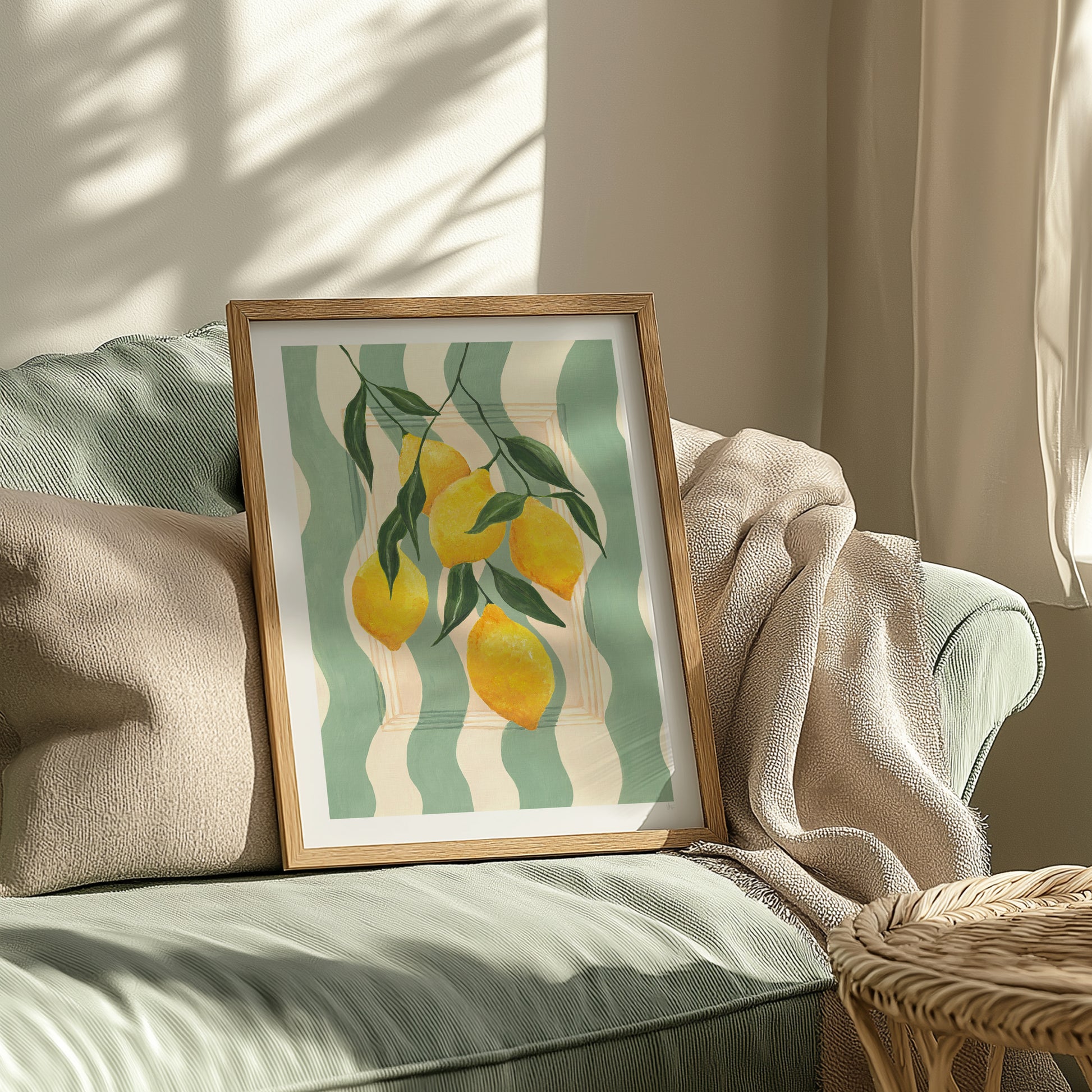 Framed artwork of lemons on a green and white striped background on a sofa.