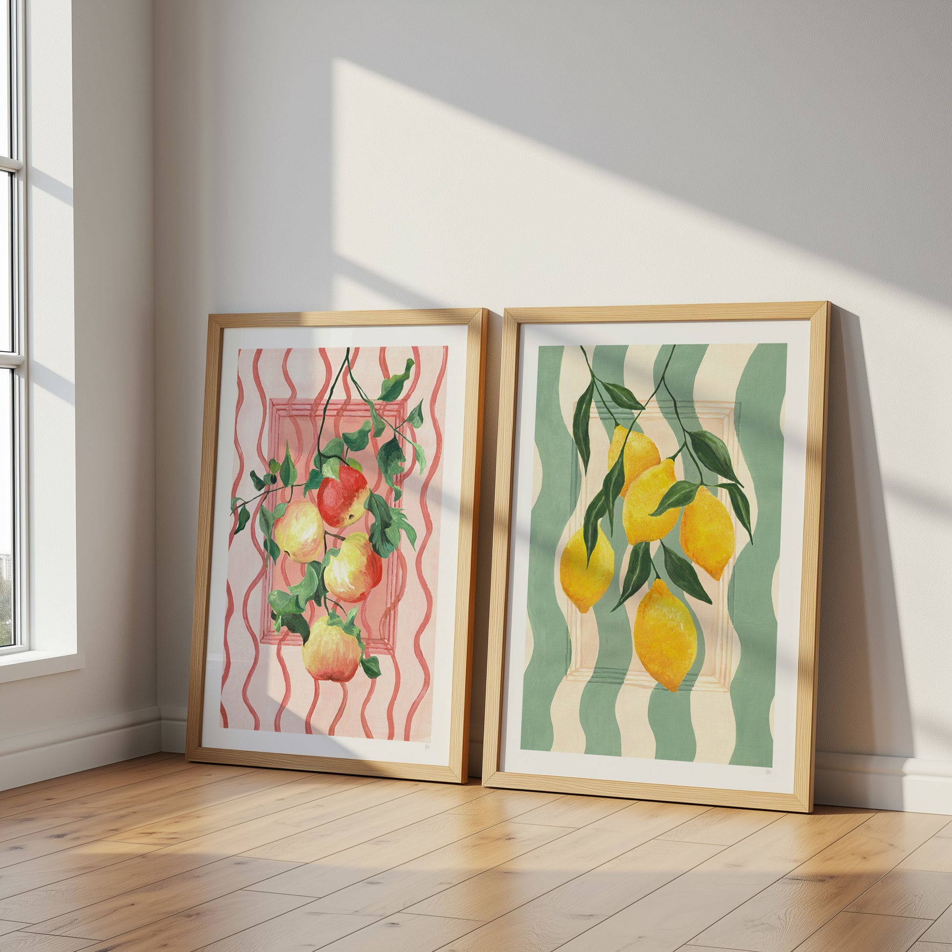 Two framed artworks of fruits on a wall with sunlight casting shadows.