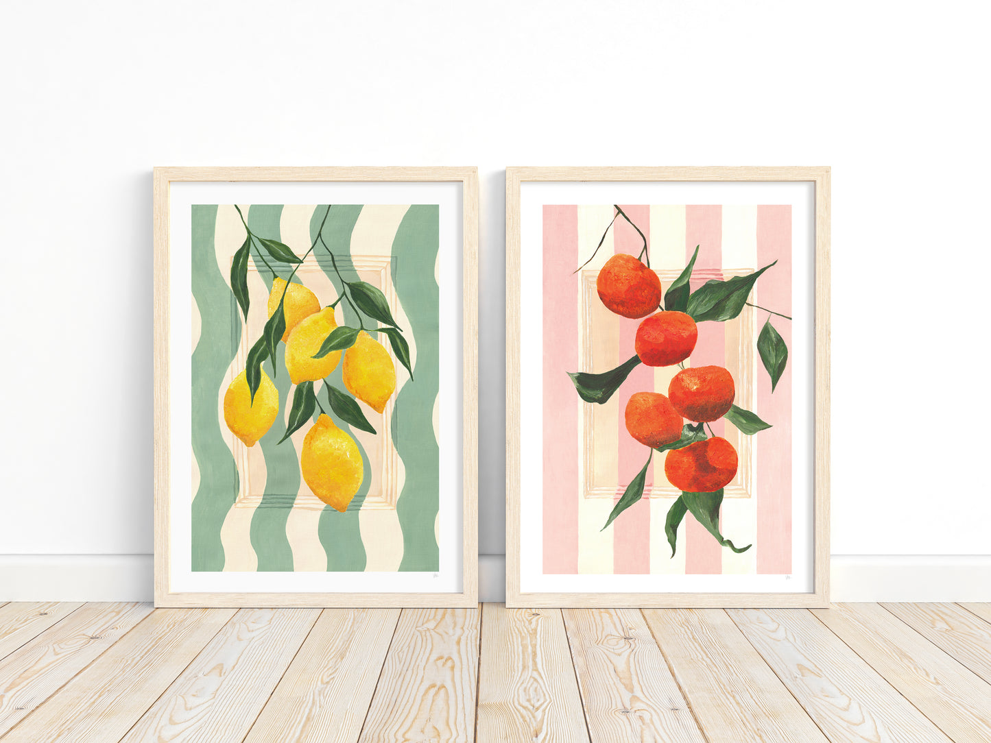 Two framed prints of lemons and tangerines on striped backgrounds.