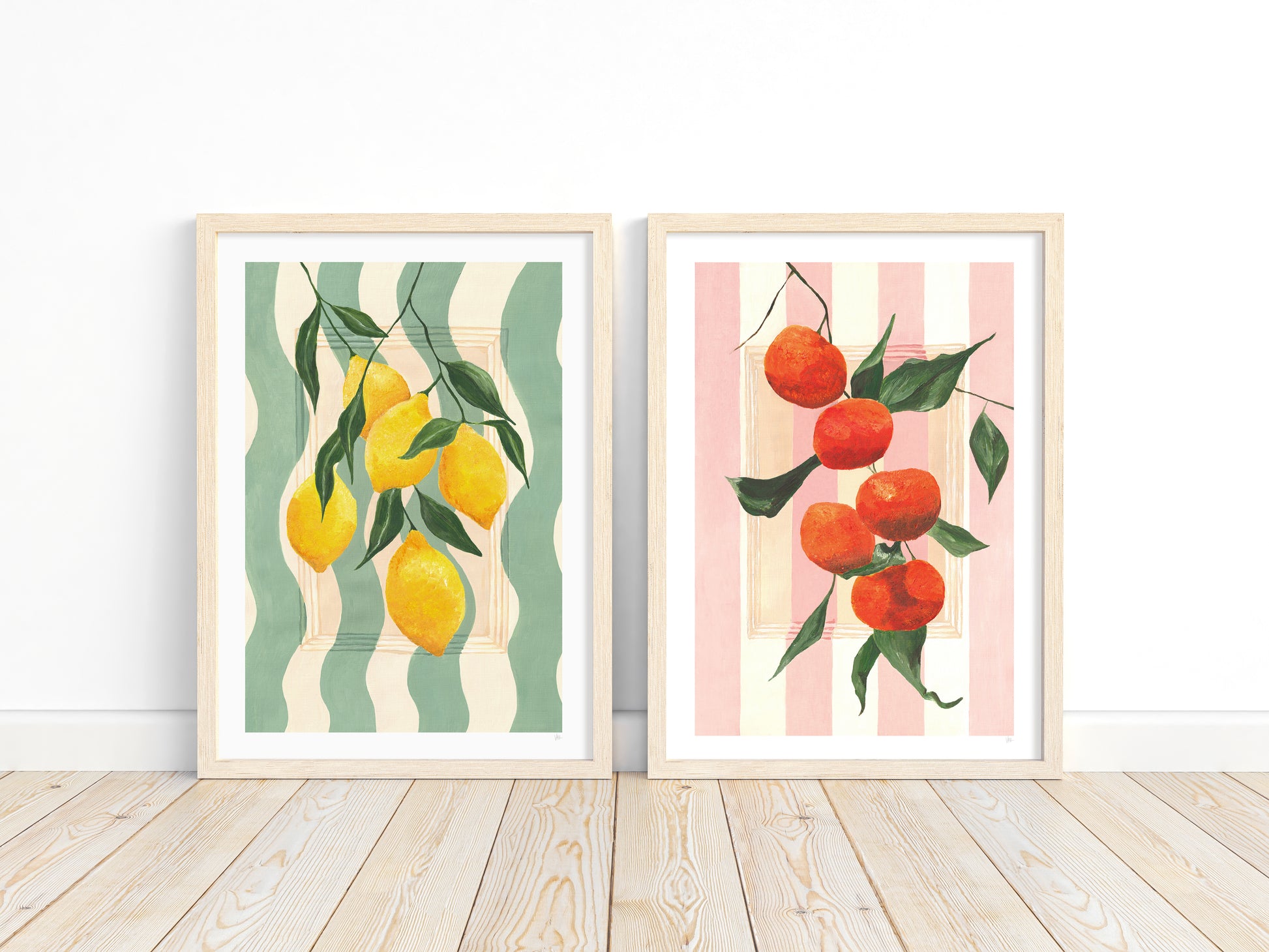Two framed prints of lemons and tangerines on striped backgrounds.
