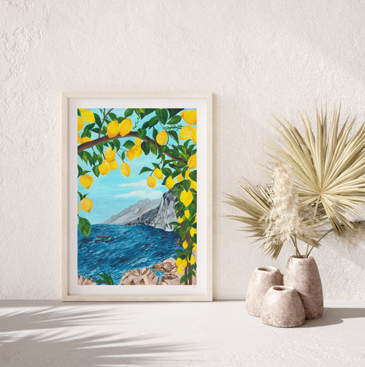 Framed artwork of a lemon tree overhanging a coastal scene with mountains, displayed on a white wall.