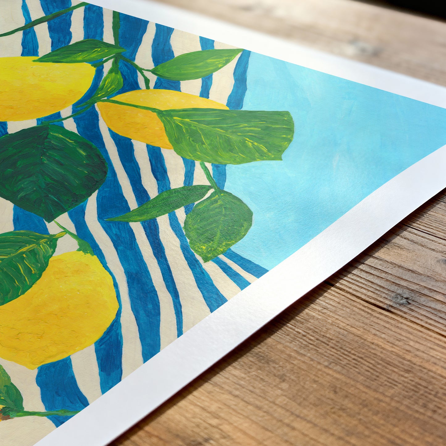 Art print with lemons and leaves on a striped background on a wooden surface