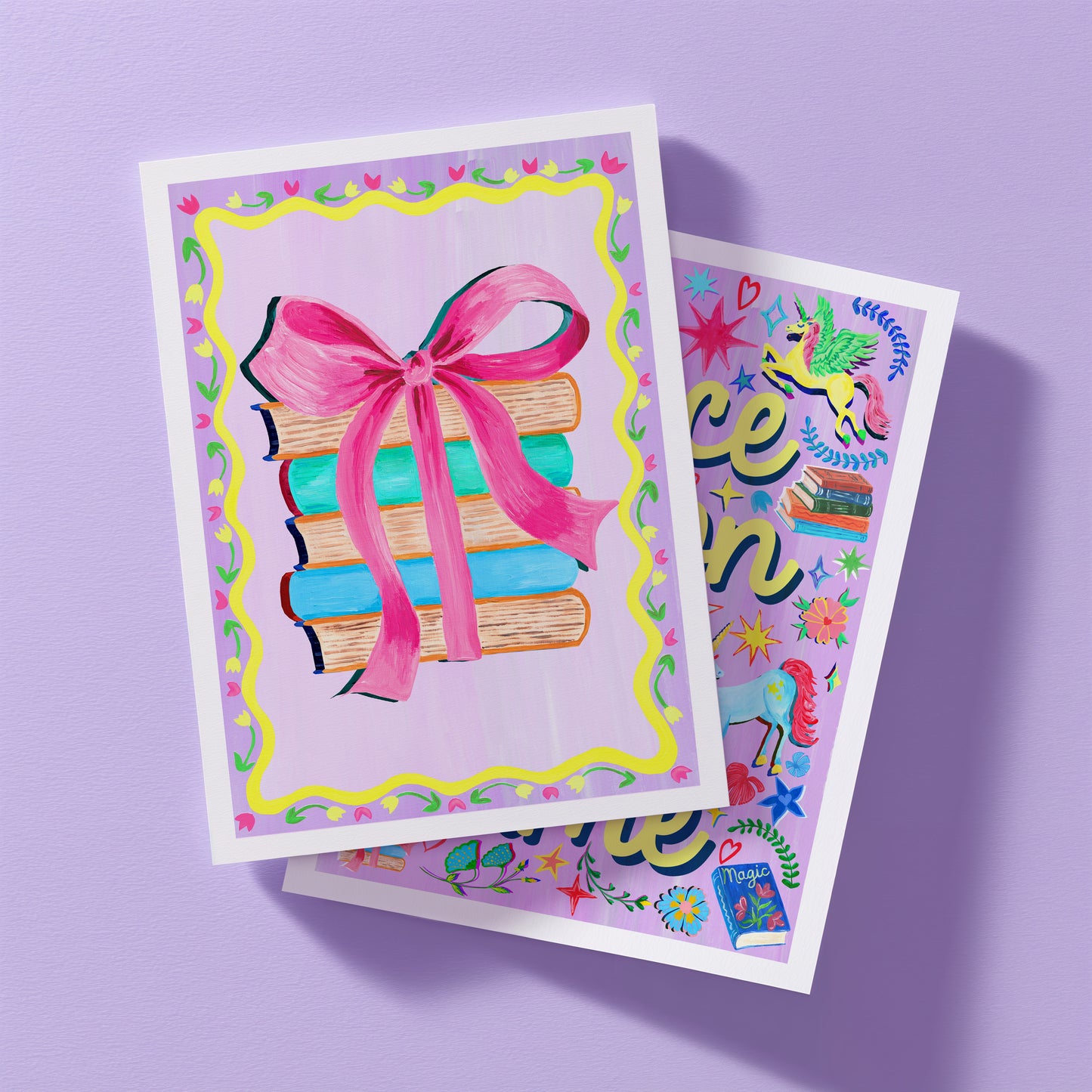 Two colorful prints with illustrations of books and a pink bow on a purple background.