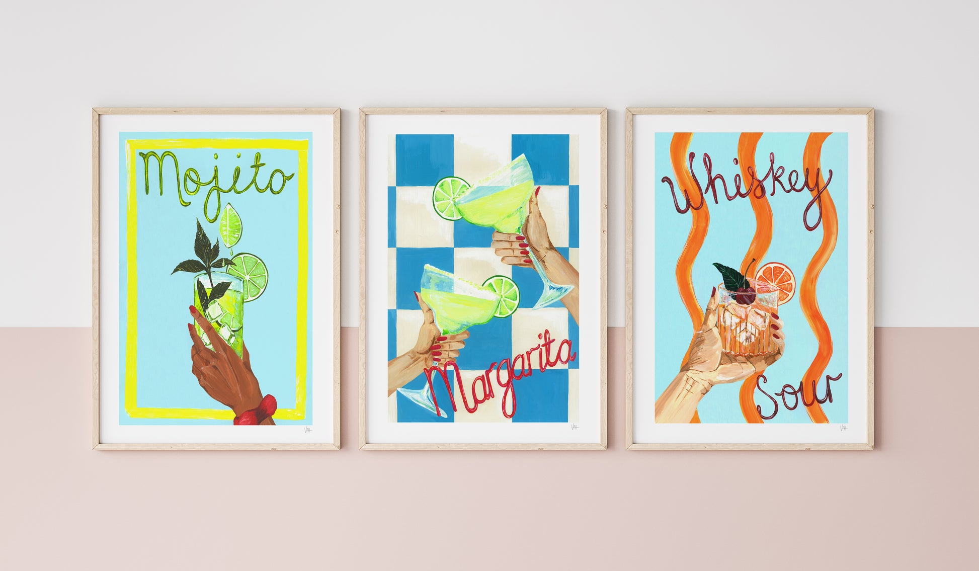 Three colorful framed prints of cocktails on a wall.
