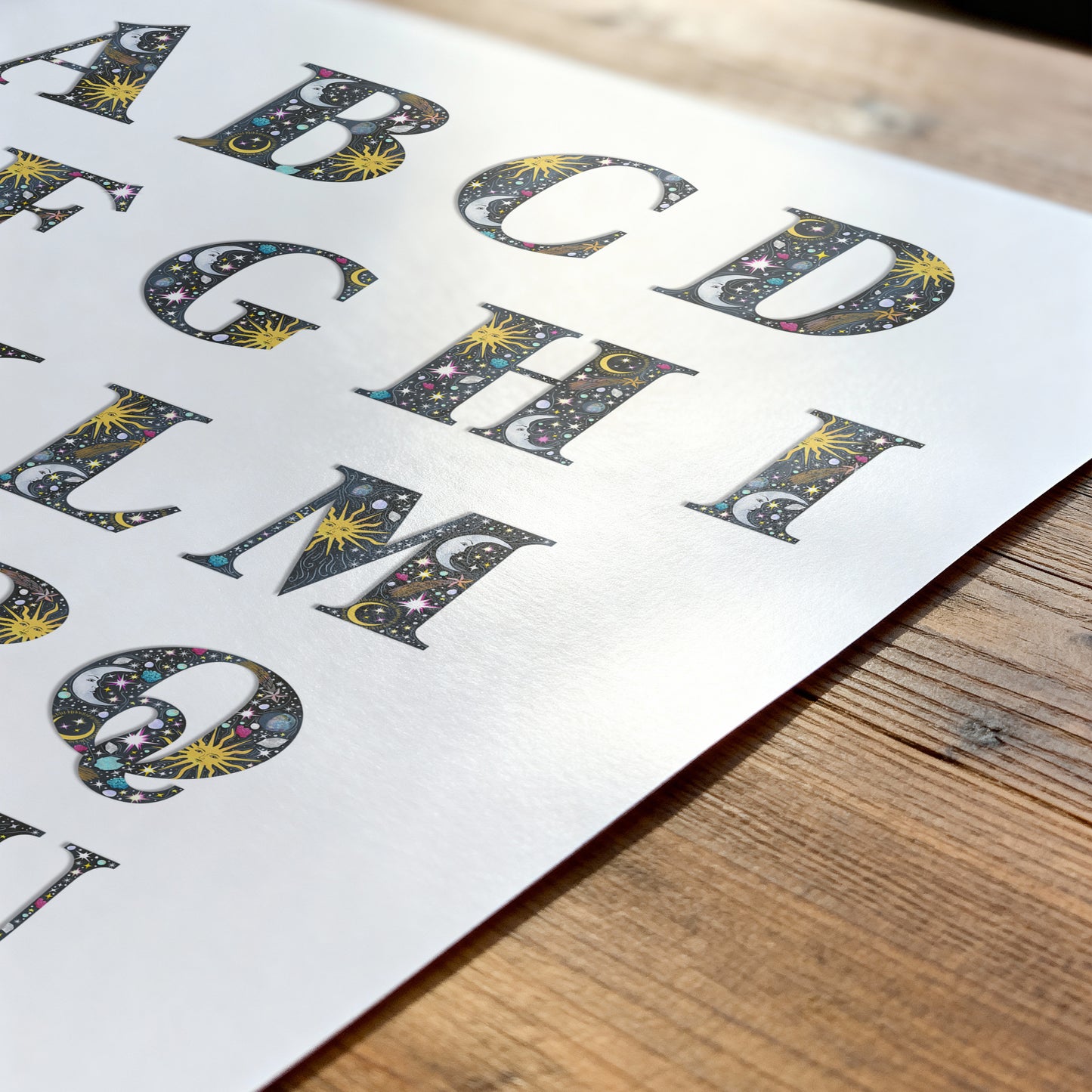 Sheet of paper with decorative letters on a wooden surface