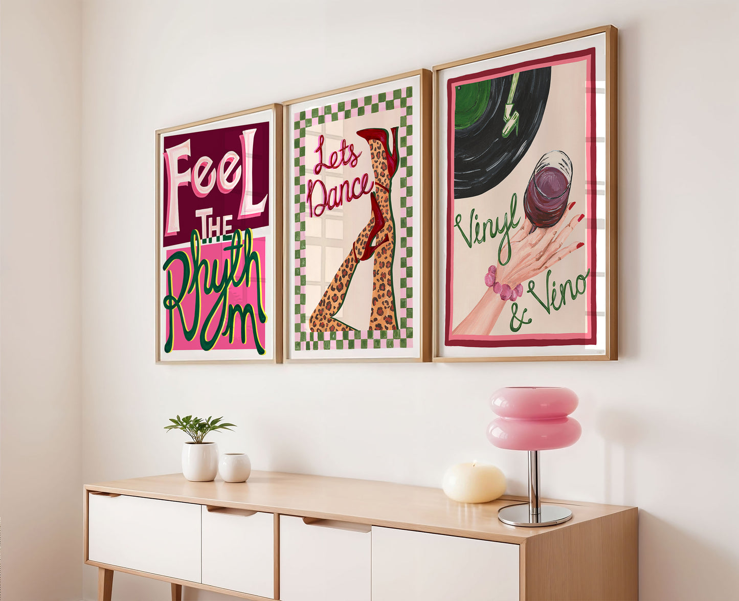 Three colorful framed posters on a wall above a wooden console table.
