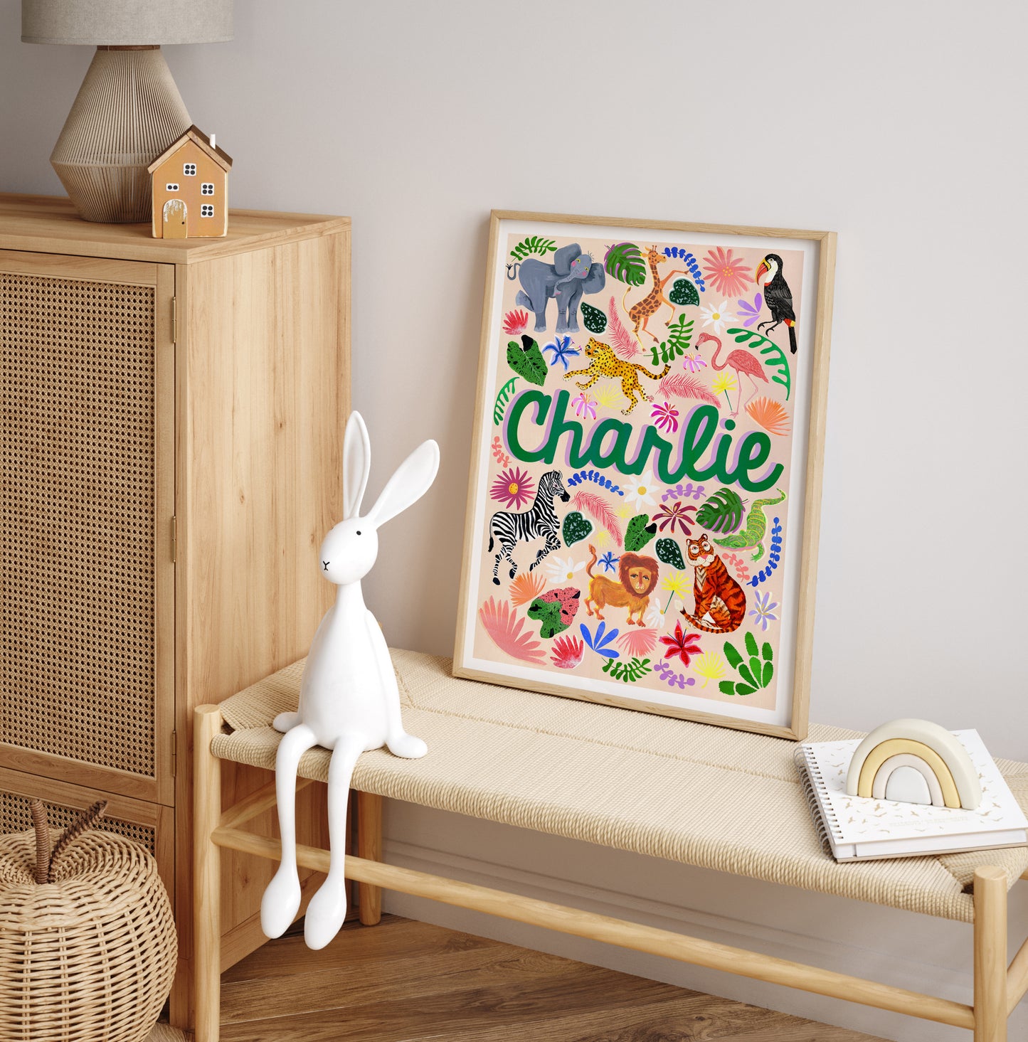 Framed children's name art with colorful animals on a wooden bench.